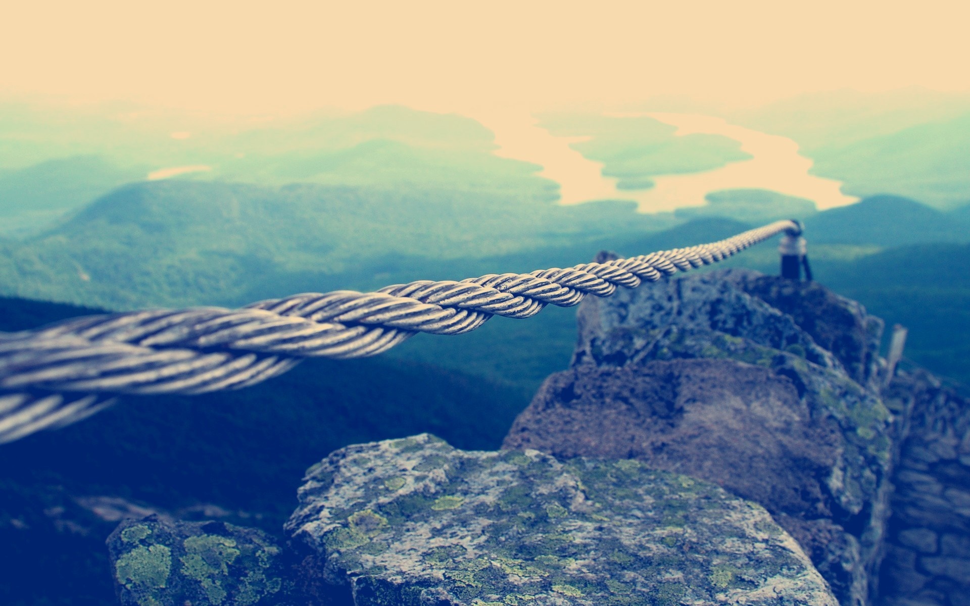 Cable railing on a rocky mountain ridge overlooking a river valley HD Wallpaper