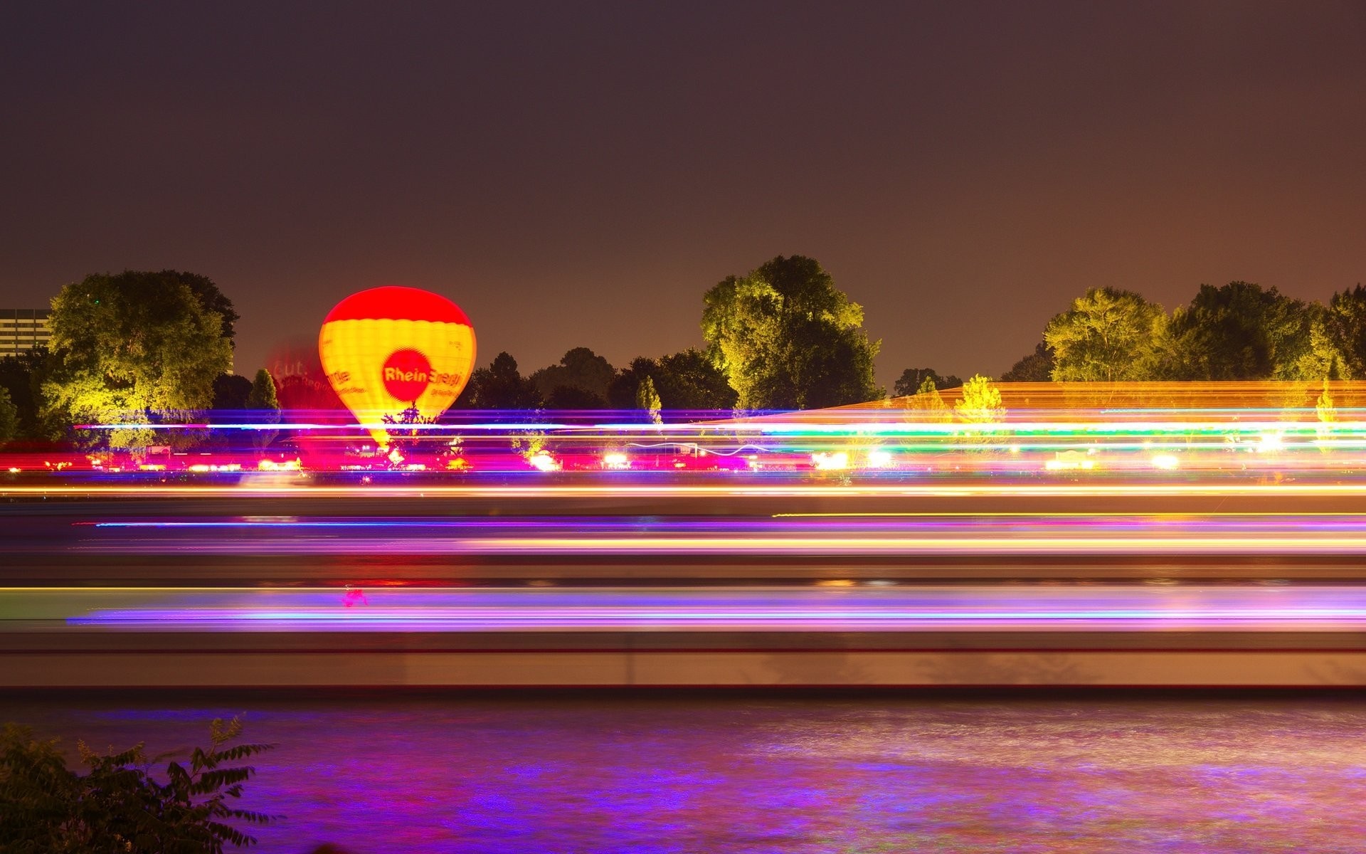 Hot air balloon over river with light trails at night HD Wallpaper