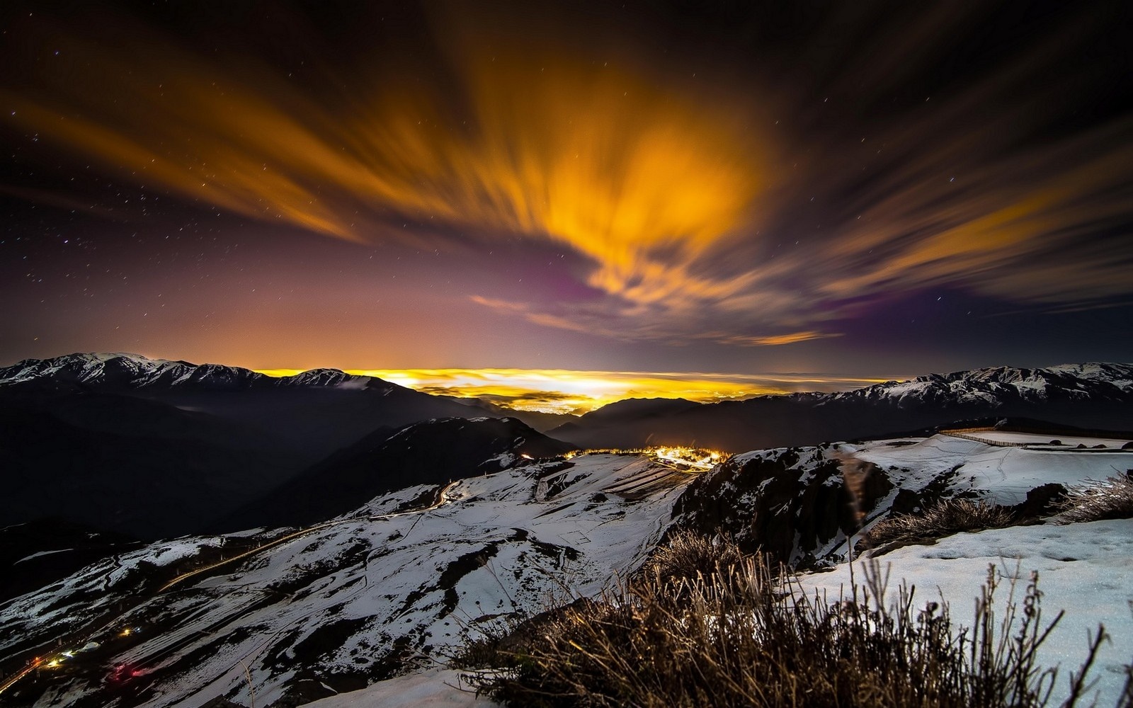 Snowy mountains at night with aurora and city lights HD Wallpaper