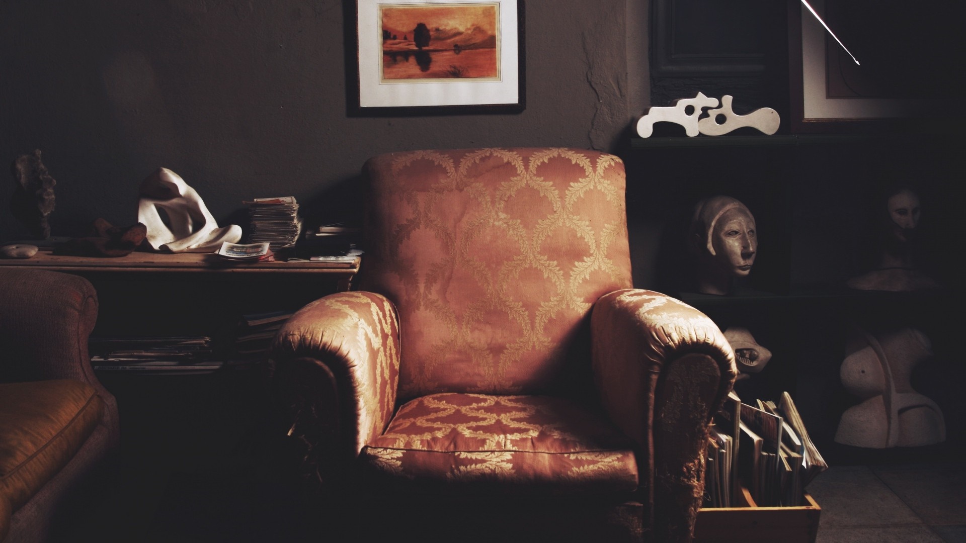 Armchair in a dimly lit room with sculptures HD Wallpaper