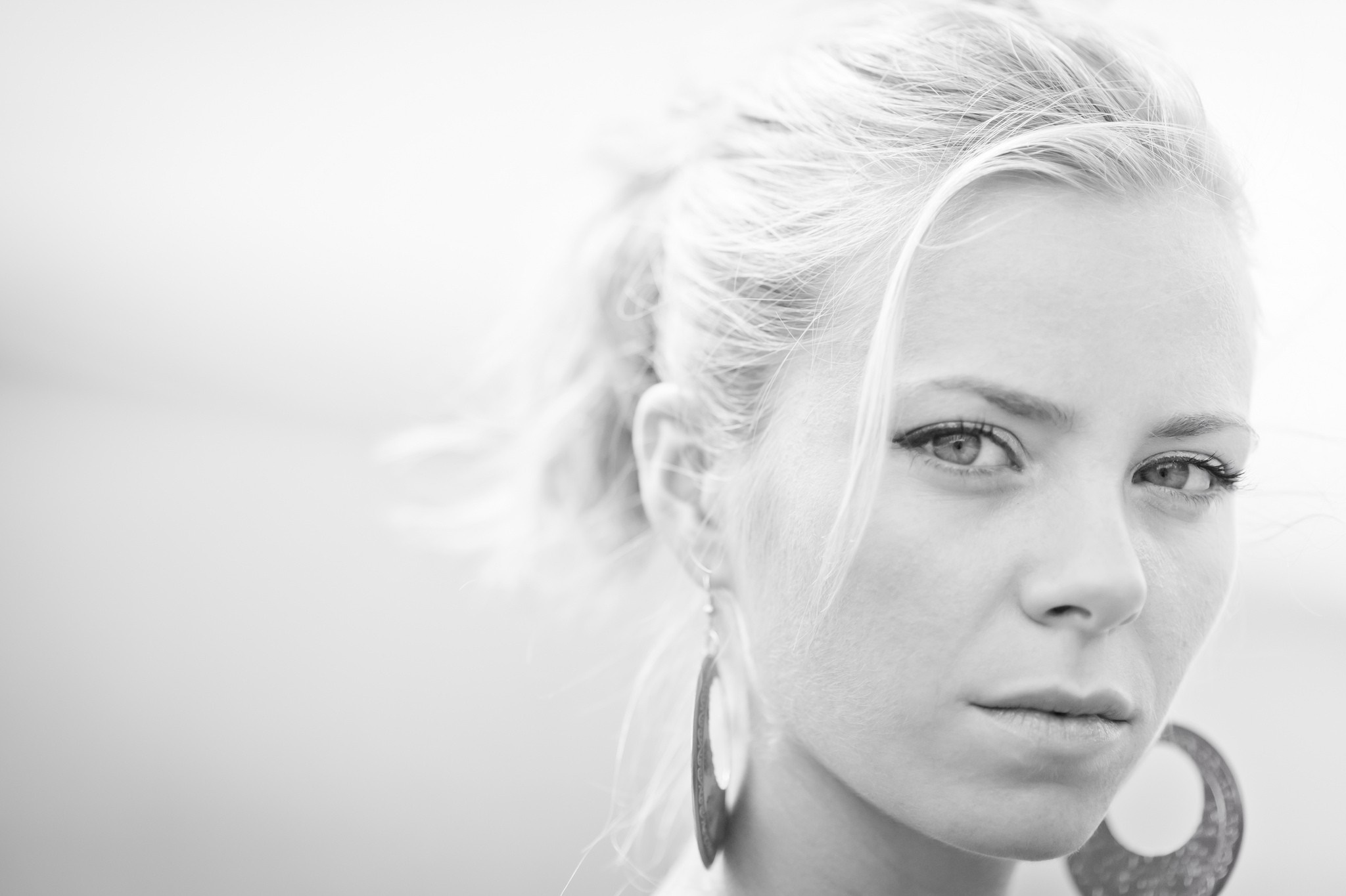 Monochrome portrait of a woman with blonde hair and large earrings HD Wallpaper