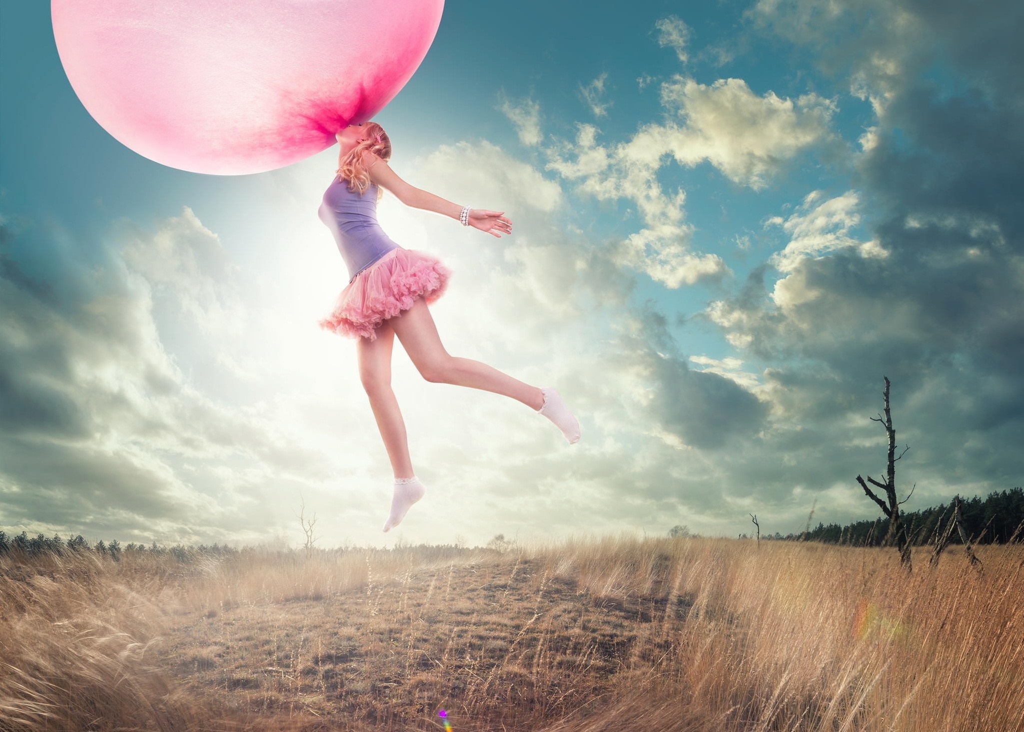 Woman blowing a giant pink bubble gum in a field HD Wallpaper