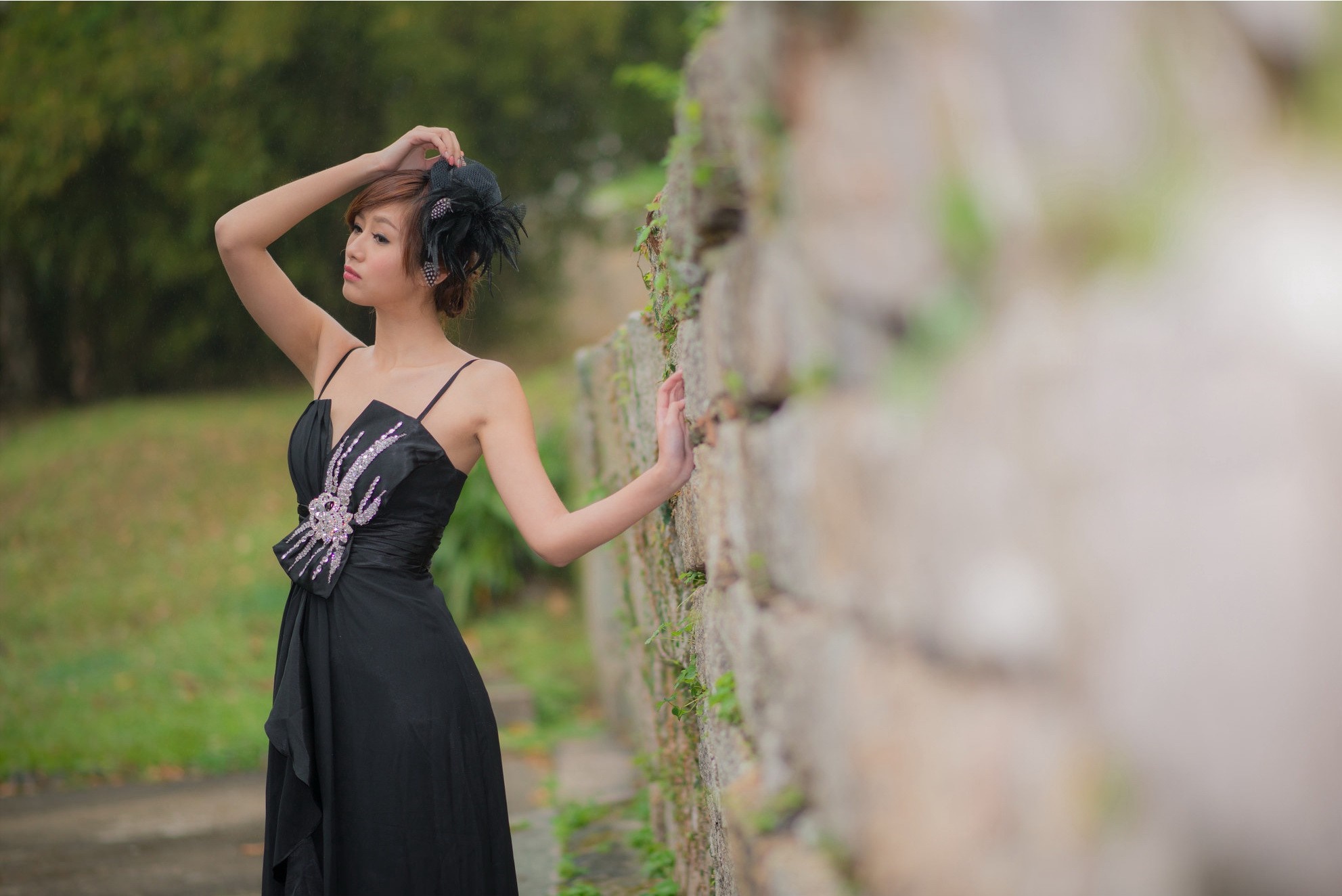 Woman in black dress posing by stone wall HD Wallpaper