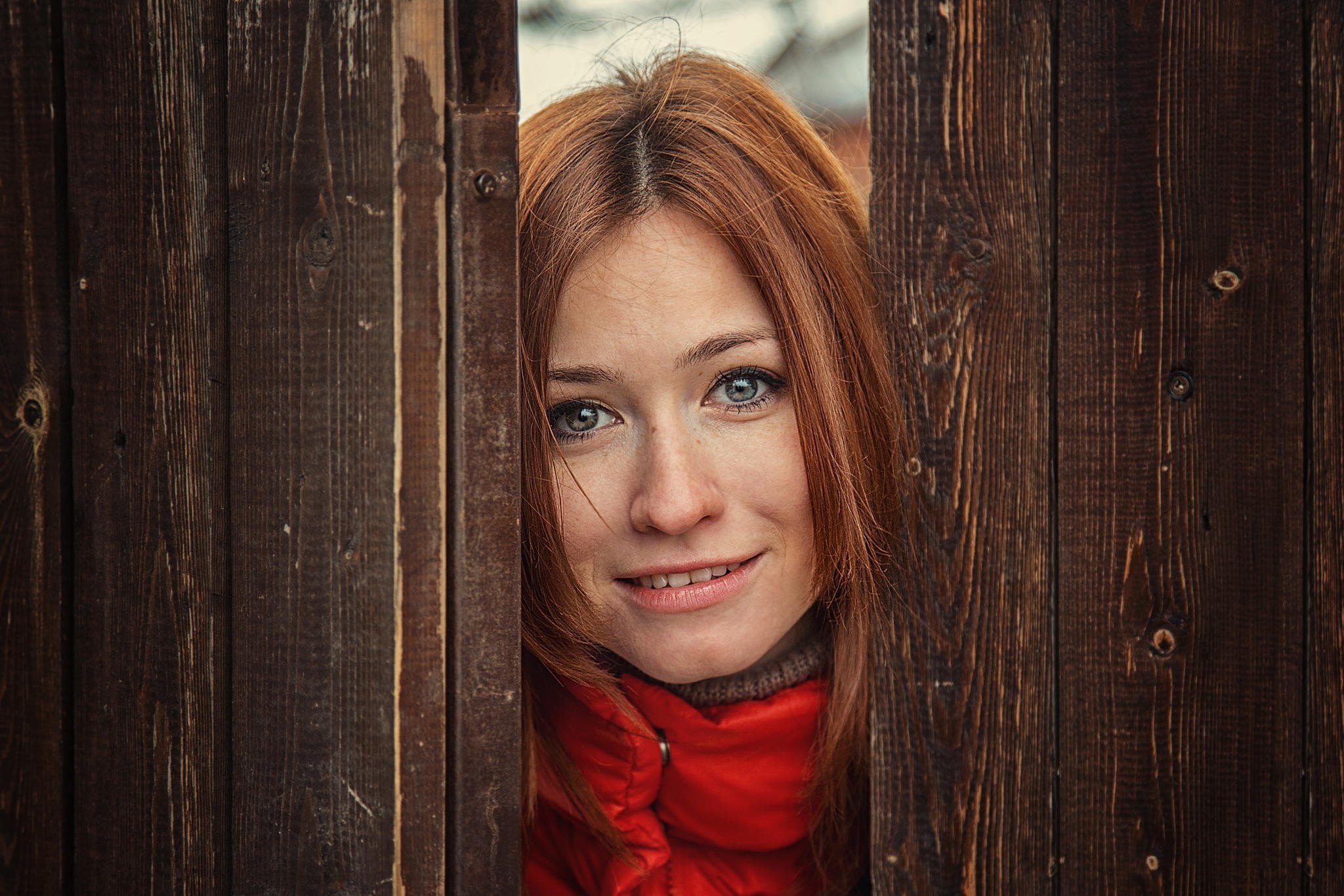 Woman with red hair peeking through wooden fence HD Wallpaper