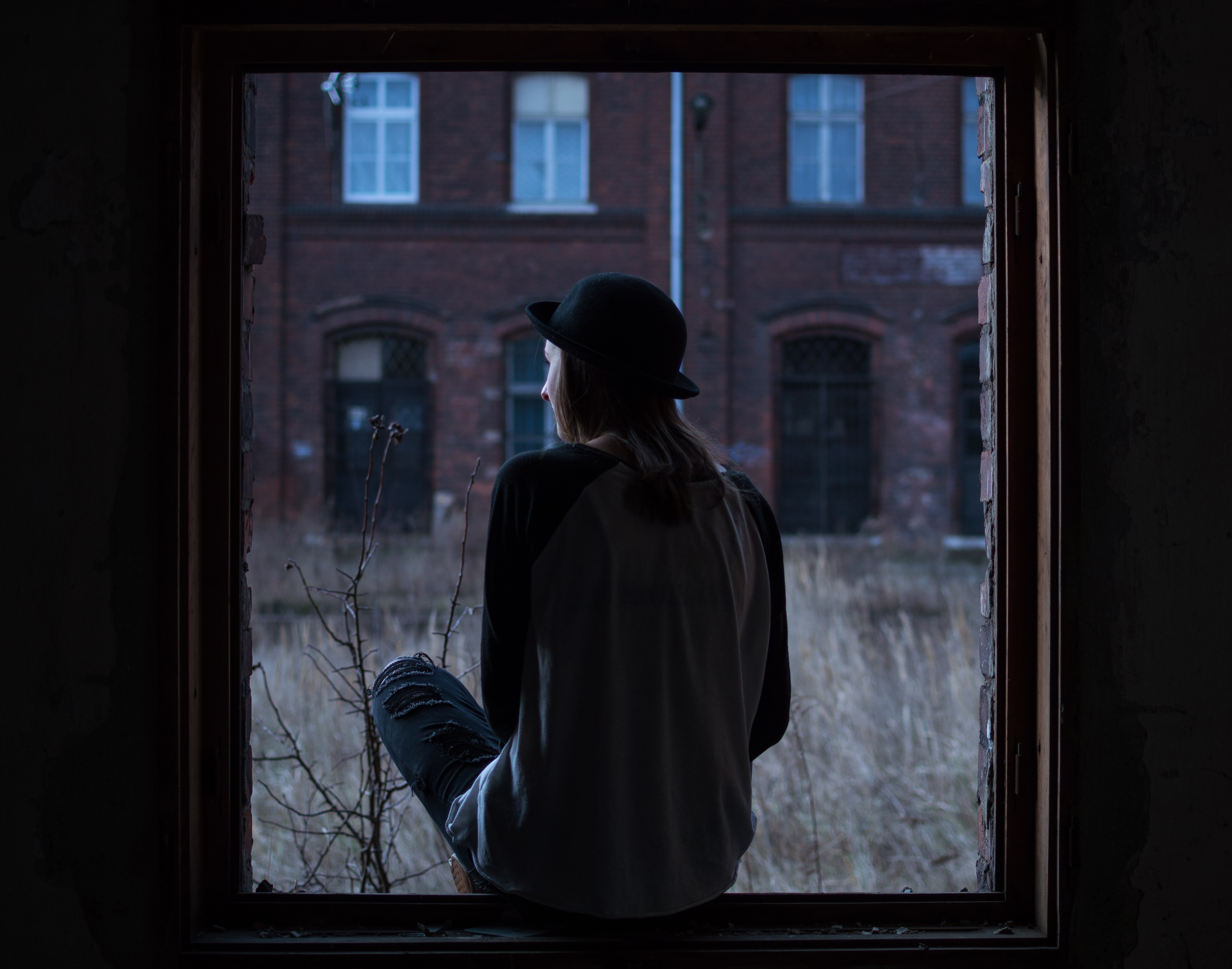 Person in hat looking out a broken window HD Wallpaper