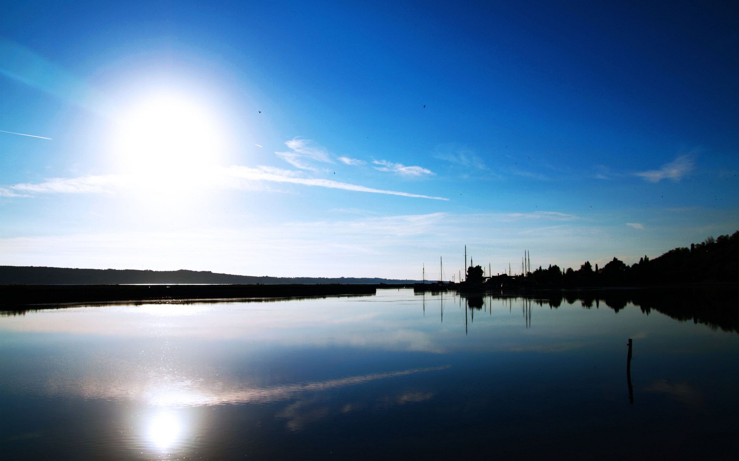 Bright Sun Reflecting on Calm Water with Silhouetted Boats HD Wallpaper
