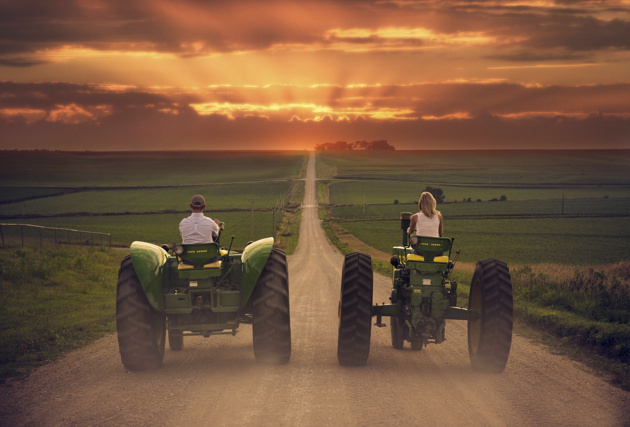 Two tractors driving on a dirt road at sunset HD Wallpaper