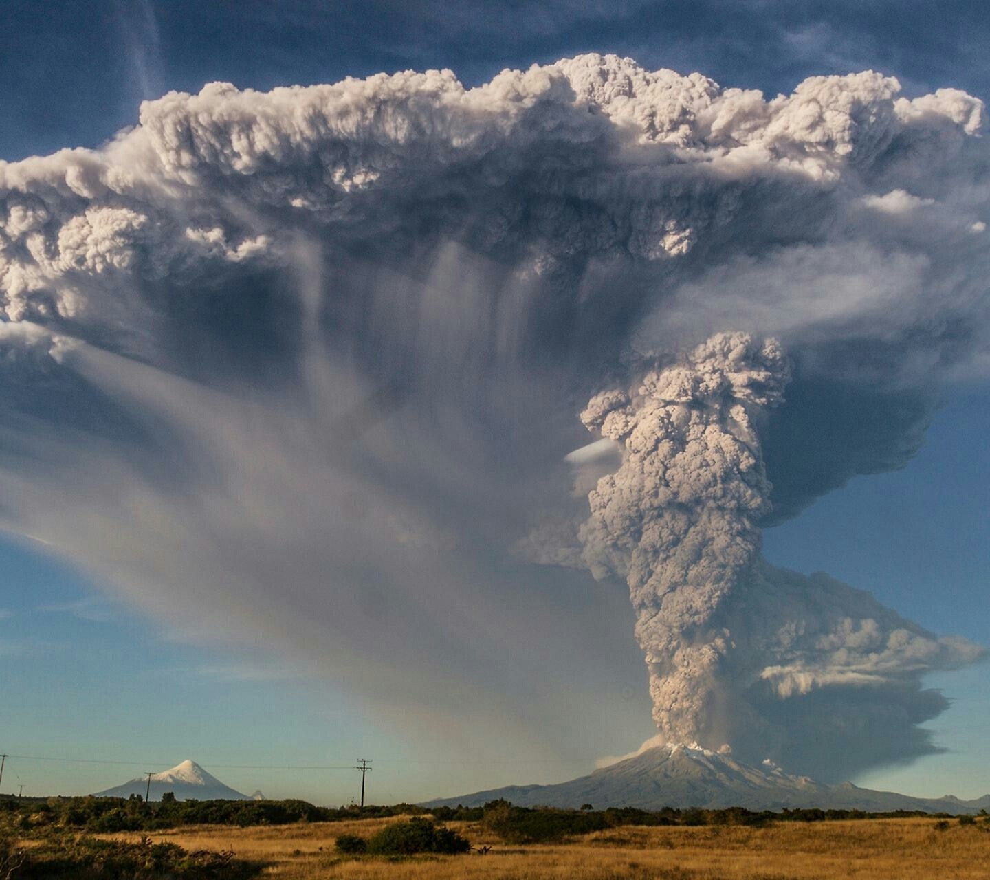 Volcanic eruption with ash cloud over mountains and plains HD Wallpaper