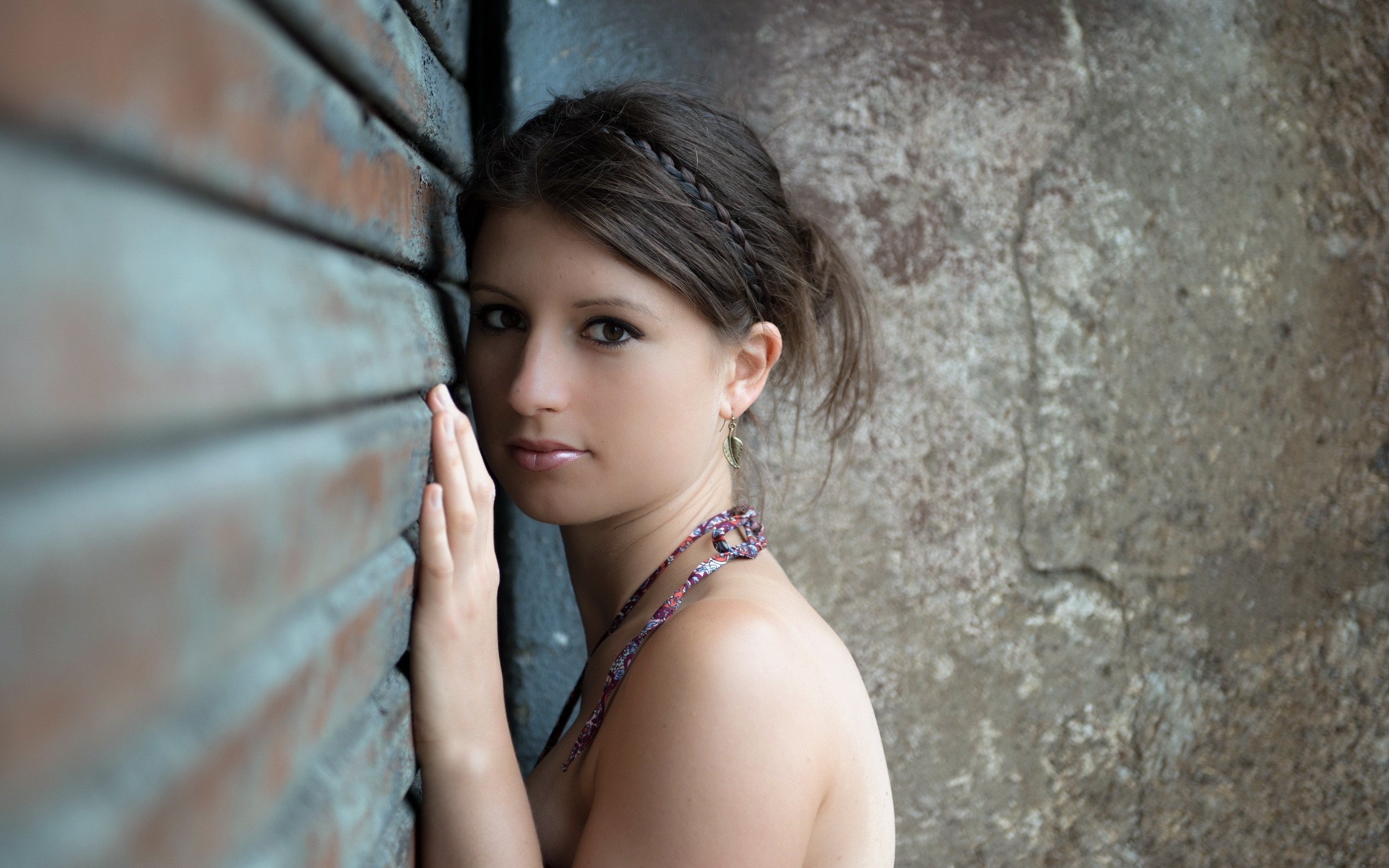 Woman leaning against a textured wall HD Wallpaper