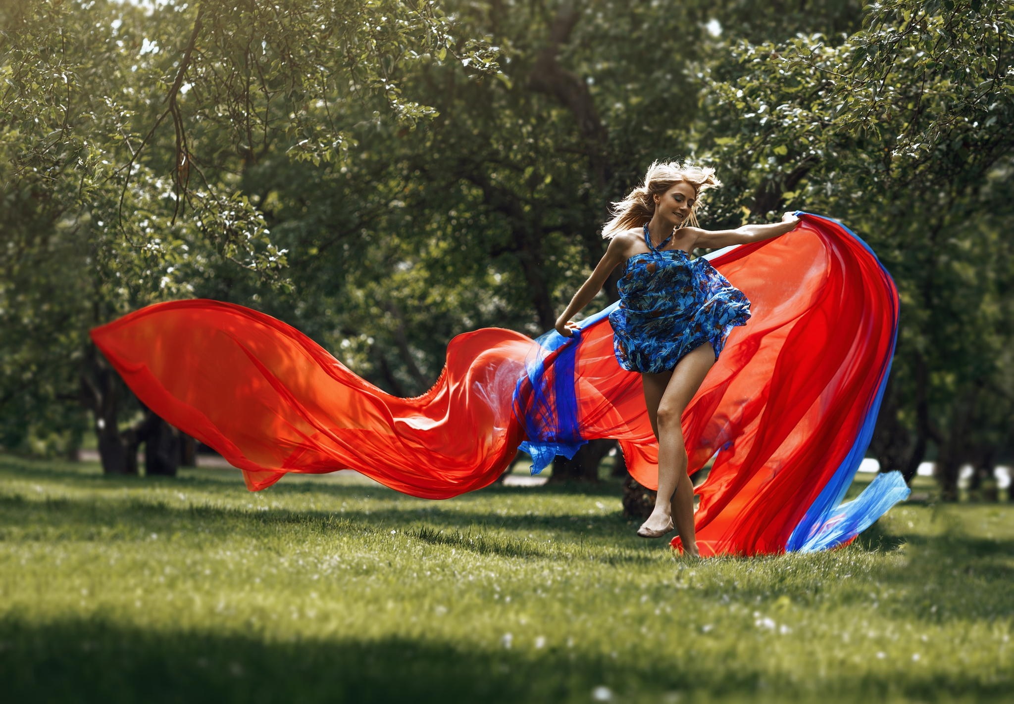 Woman in blue dress with red and blue fabric in a park HD Wallpaper