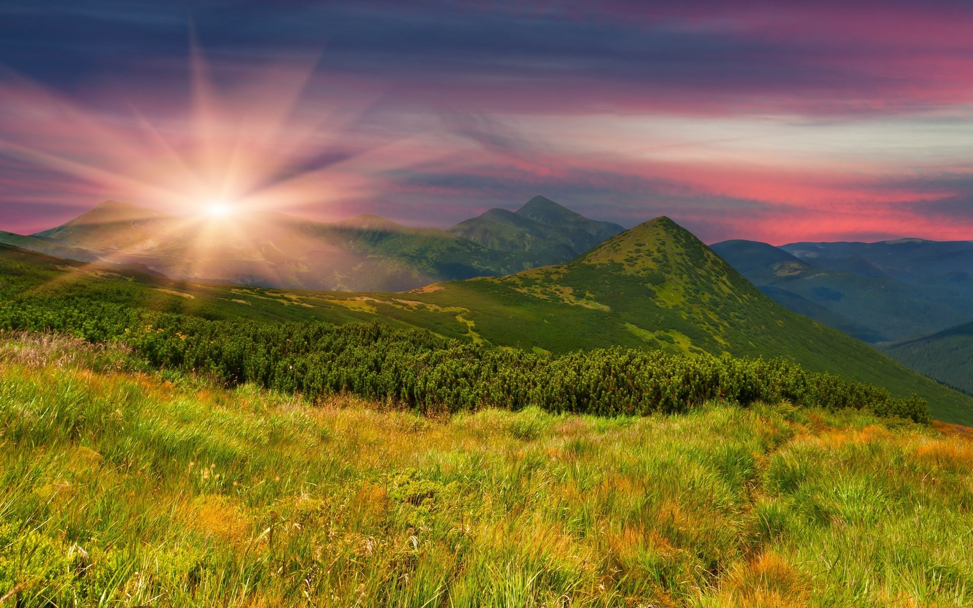Sunrise over a mountain range with green hills HD Wallpaper