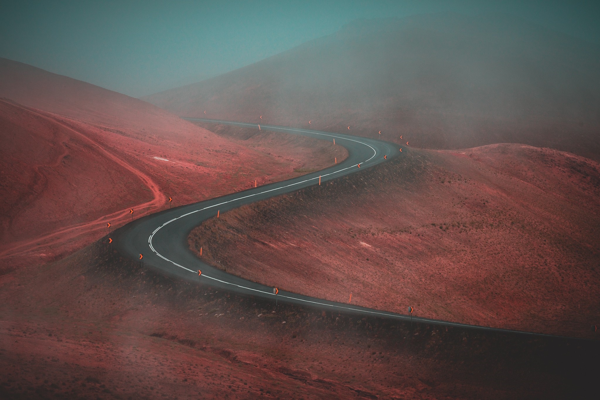 Winding road through red hills in fog HD Wallpaper