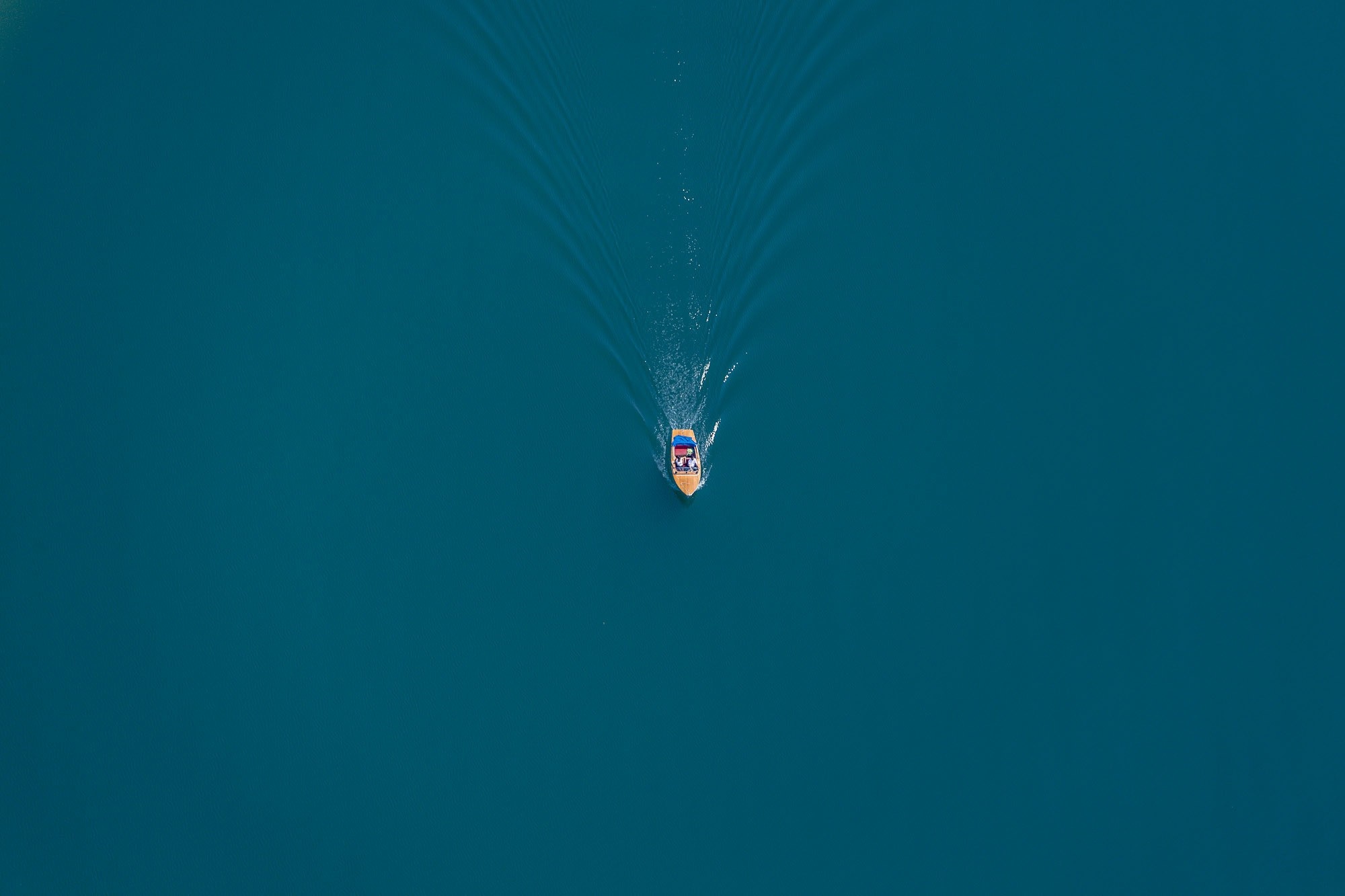 Boat on a blue lake creating ripples HD Wallpaper