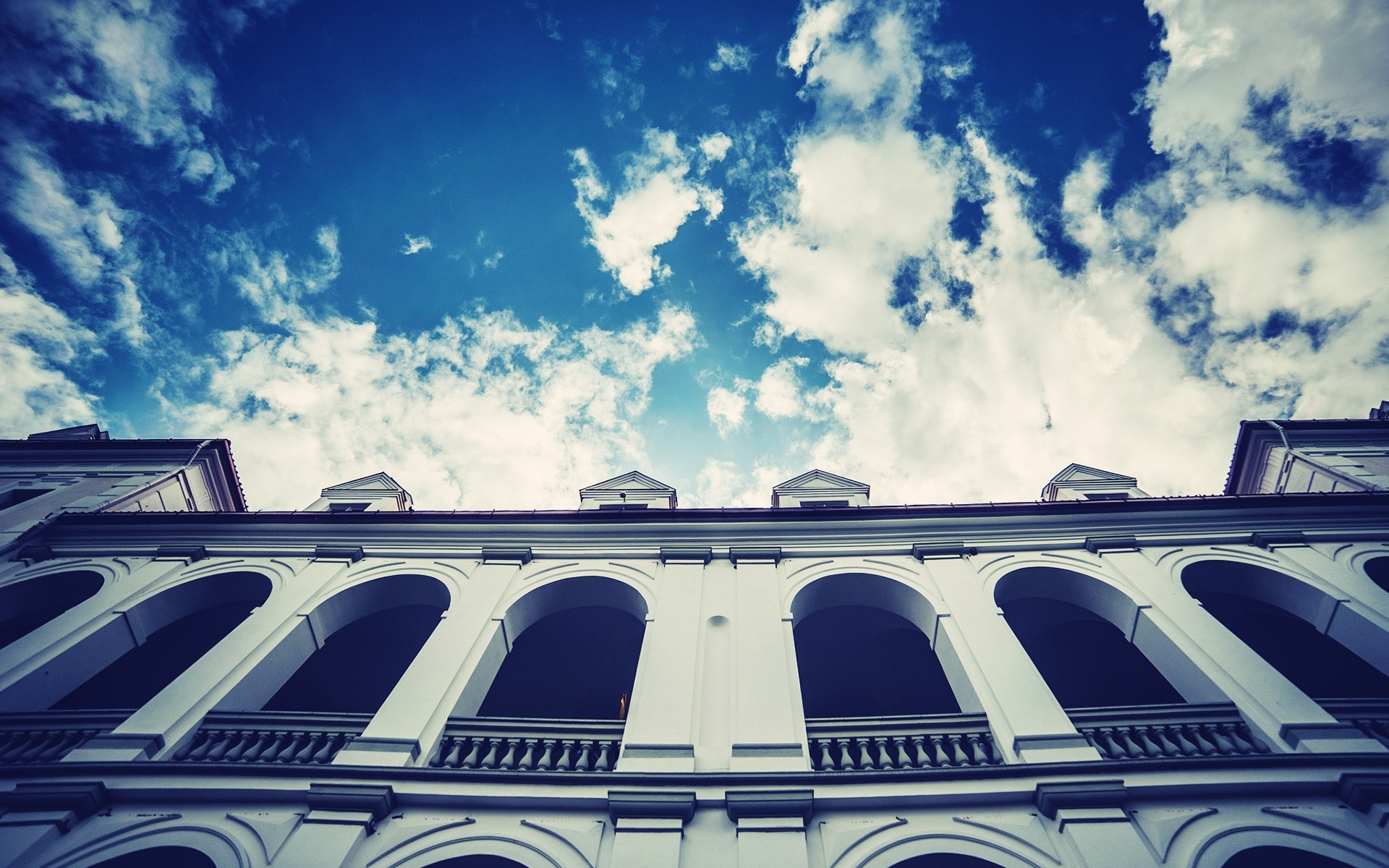 White building with arched windows against a blue sky with clouds HD Wallpaper