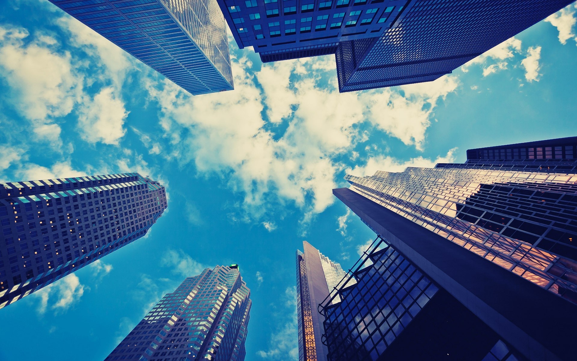 Looking up at skyscrapers against a blue sky with clouds HD Wallpaper