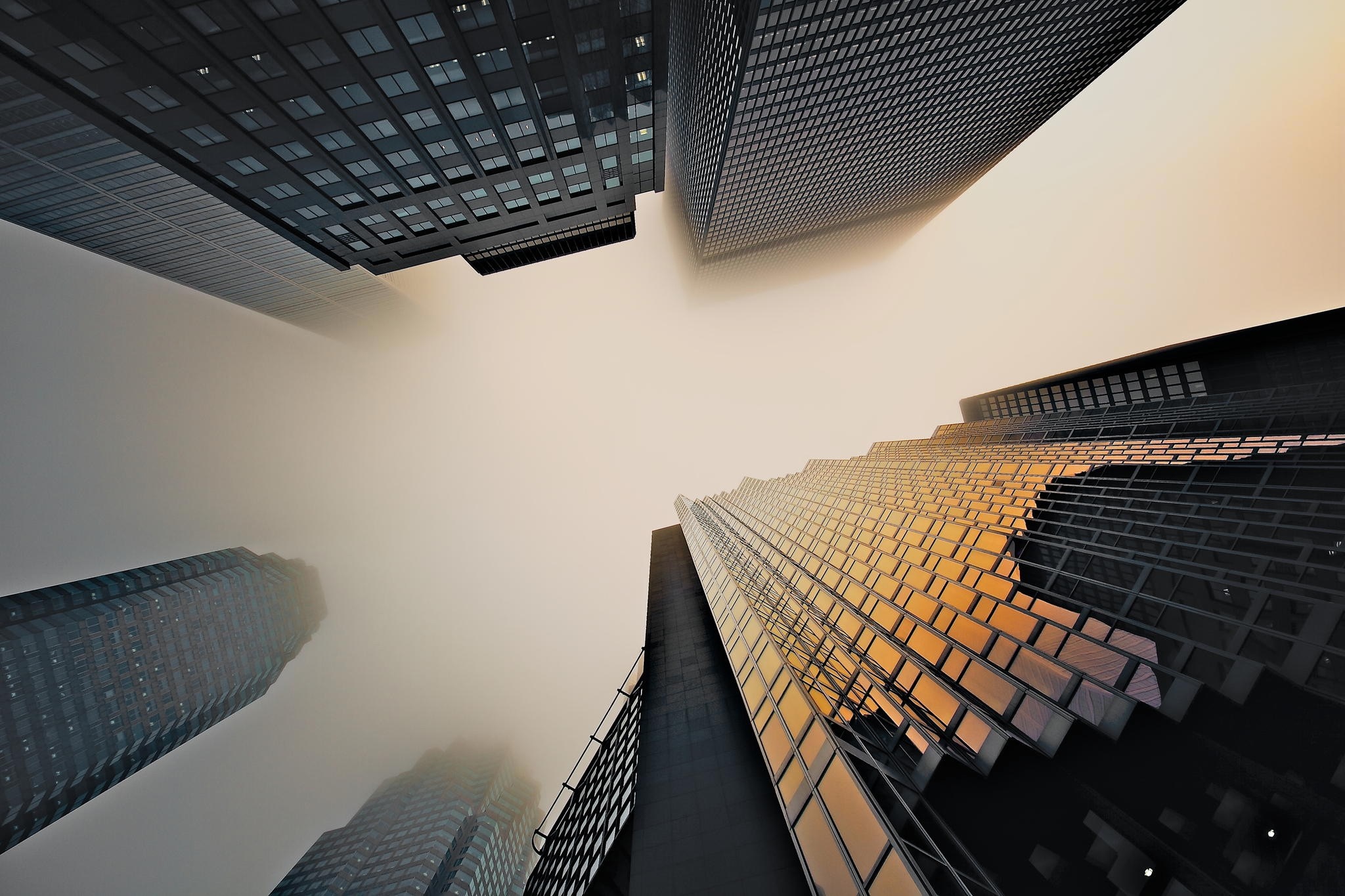 Skyscrapers shrouded in mist, viewed from below HD Wallpaper