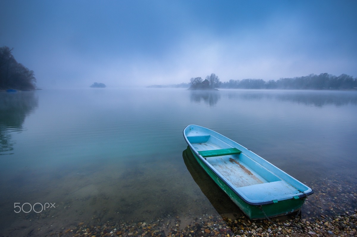 A lone boat on a misty lake at dawn HD Wallpaper