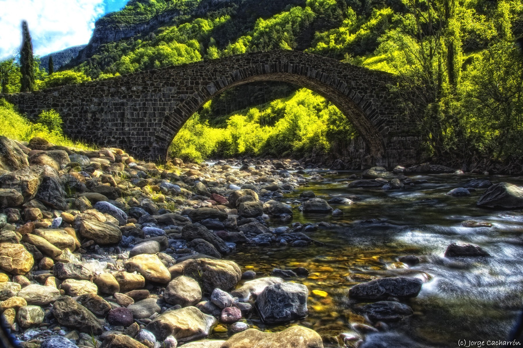Stone bridge over a rocky river in a green valley HD Wallpaper