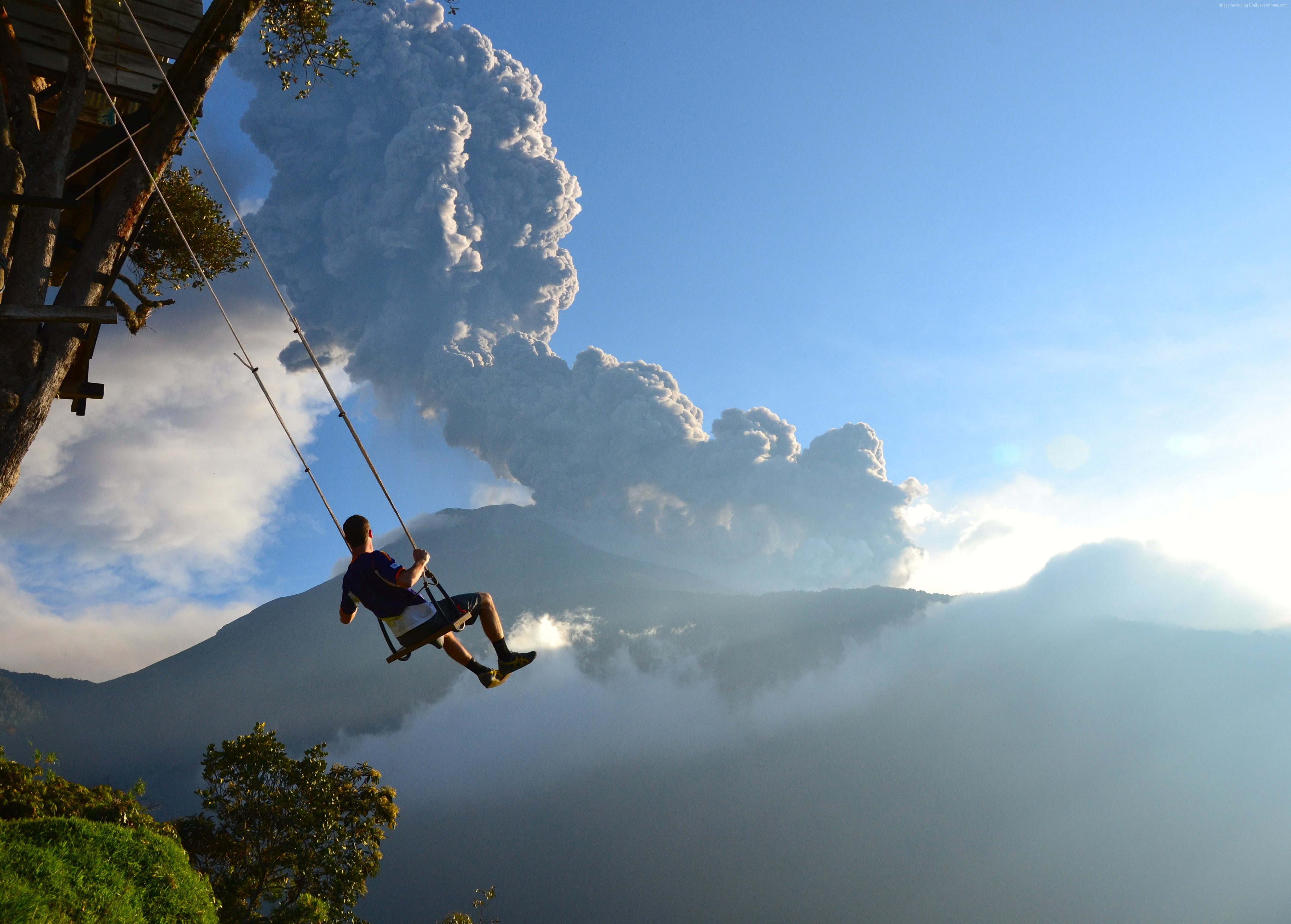 Man on swing with volcano eruption HD Wallpaper