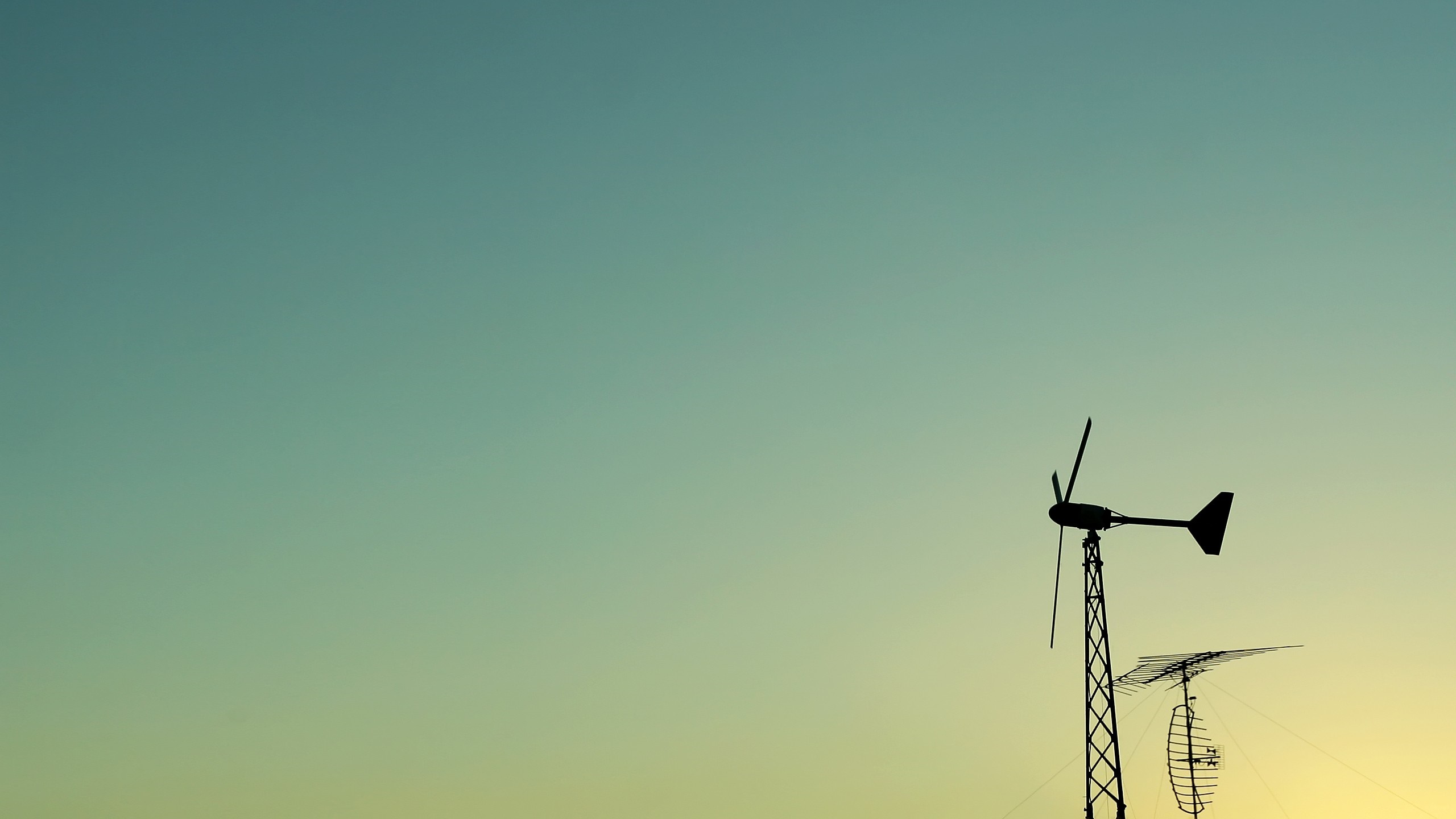 Silhouette of a wind turbine and antenna against a gradient sky HD Wallpaper