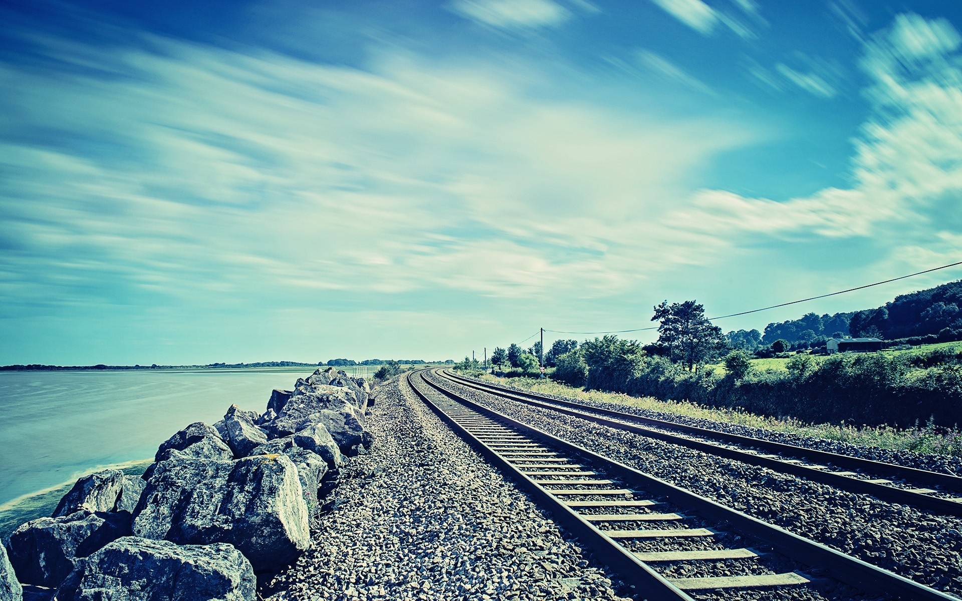 Railway tracks along the sea with a cloudy sky HD Wallpaper