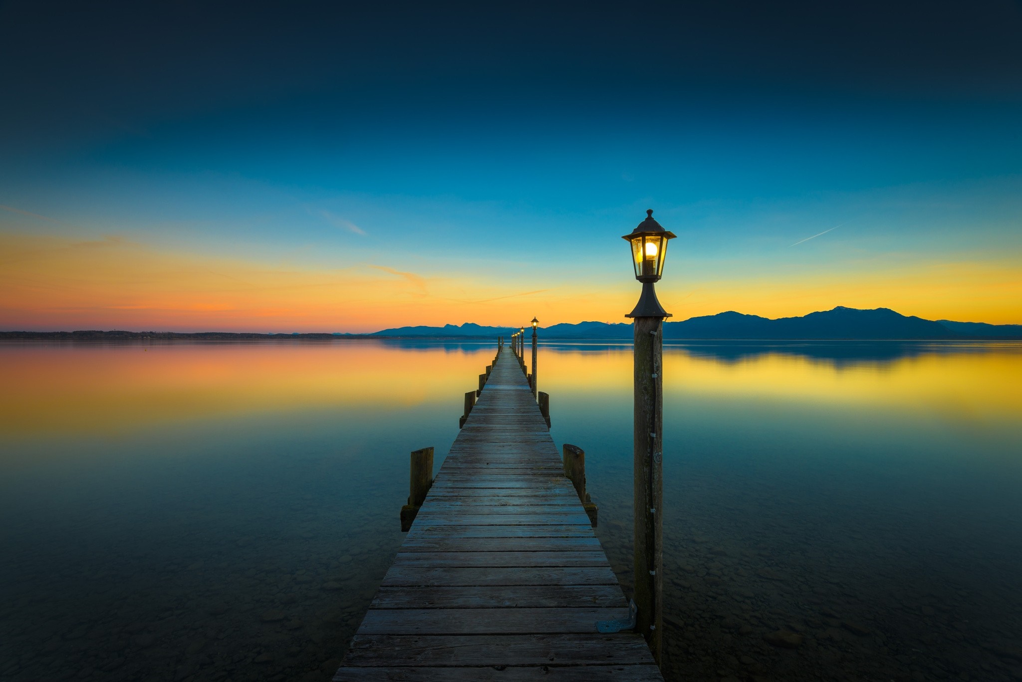 Wooden pier with lamps at sunset over a lake HD Wallpaper