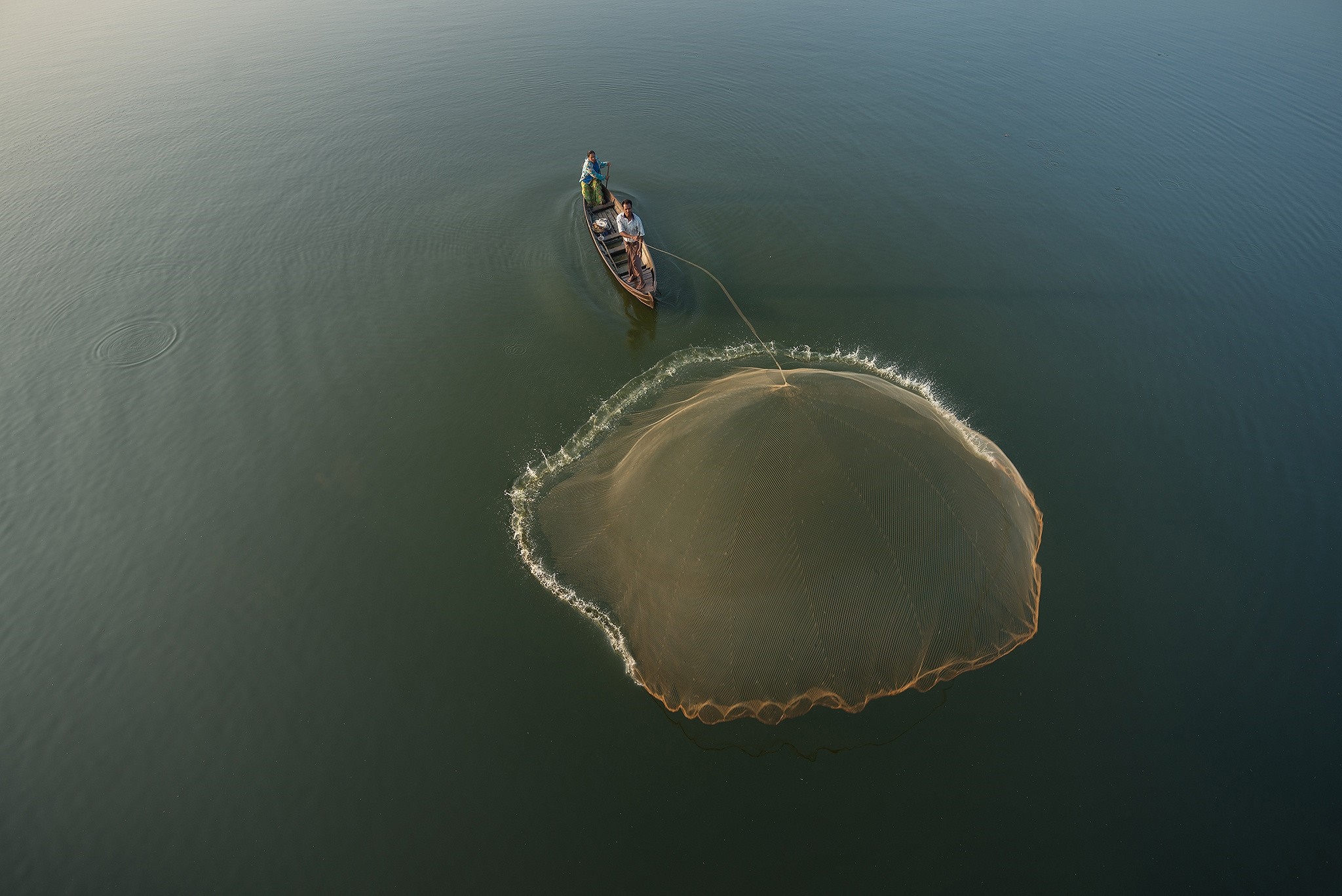 Fishermen casting a net from a boat on the water HD Wallpaper