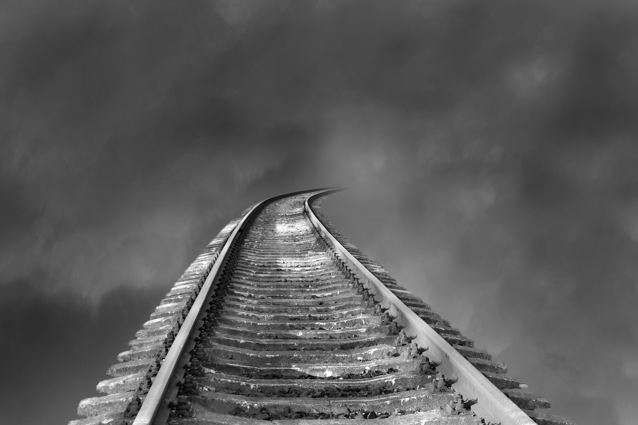 Railroad tracks curving into dark, cloudy sky HD Wallpaper