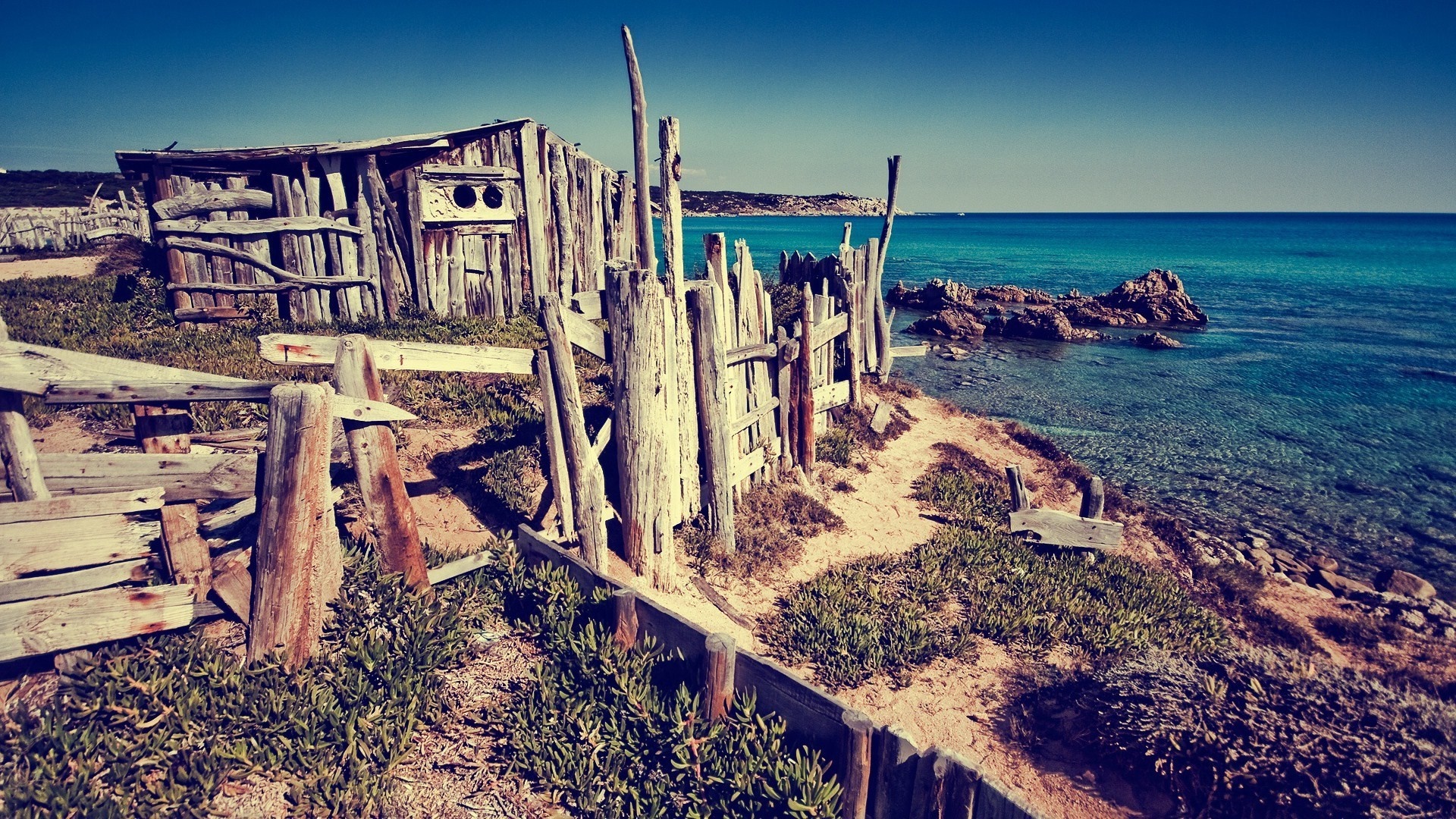 Rustic wooden shack on a rocky coast overlooking the sea HD Wallpaper