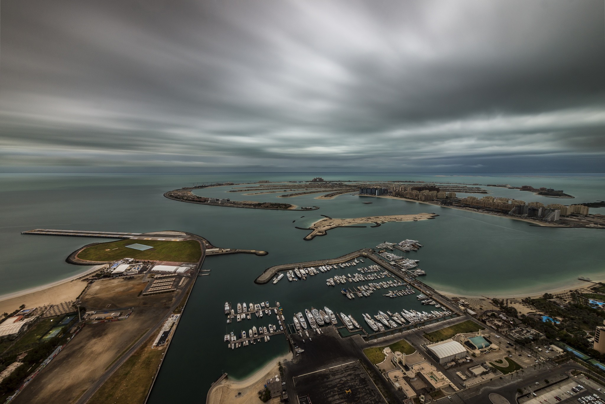 Aerial view of Palm Jumeirah, Dubai with yachts and cloudy sky HD Wallpaper