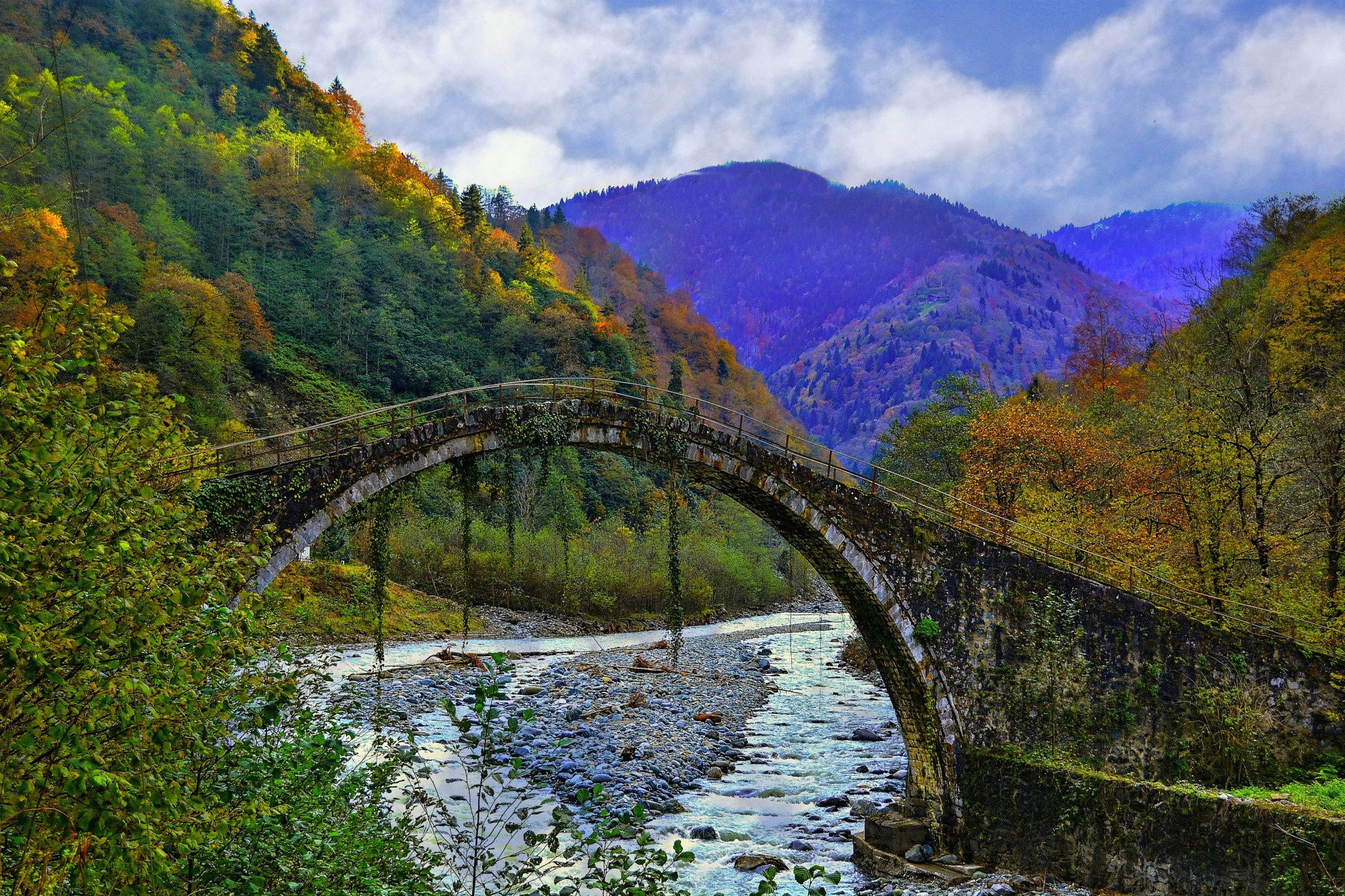 Stone bridge over a river in a mountain valley during autumn HD Wallpaper