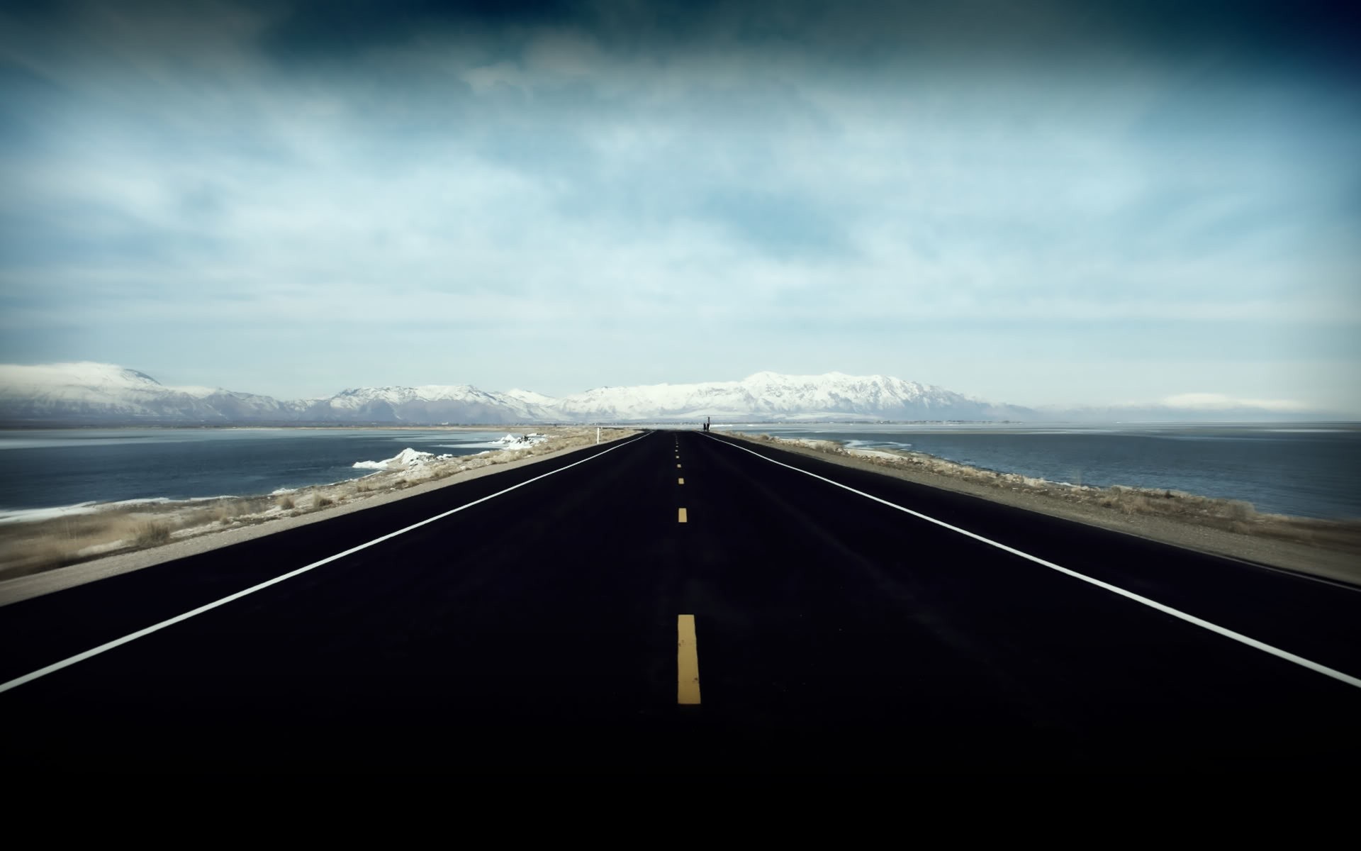 Empty highway by the sea with snow-capped mountains HD Wallpaper