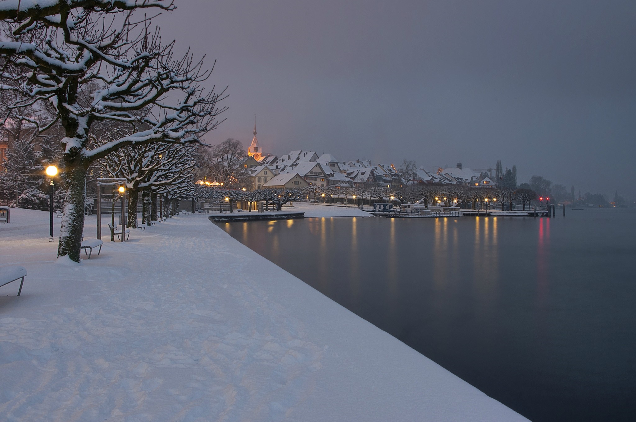 Snowy waterfront town at dusk with reflections HD Wallpaper