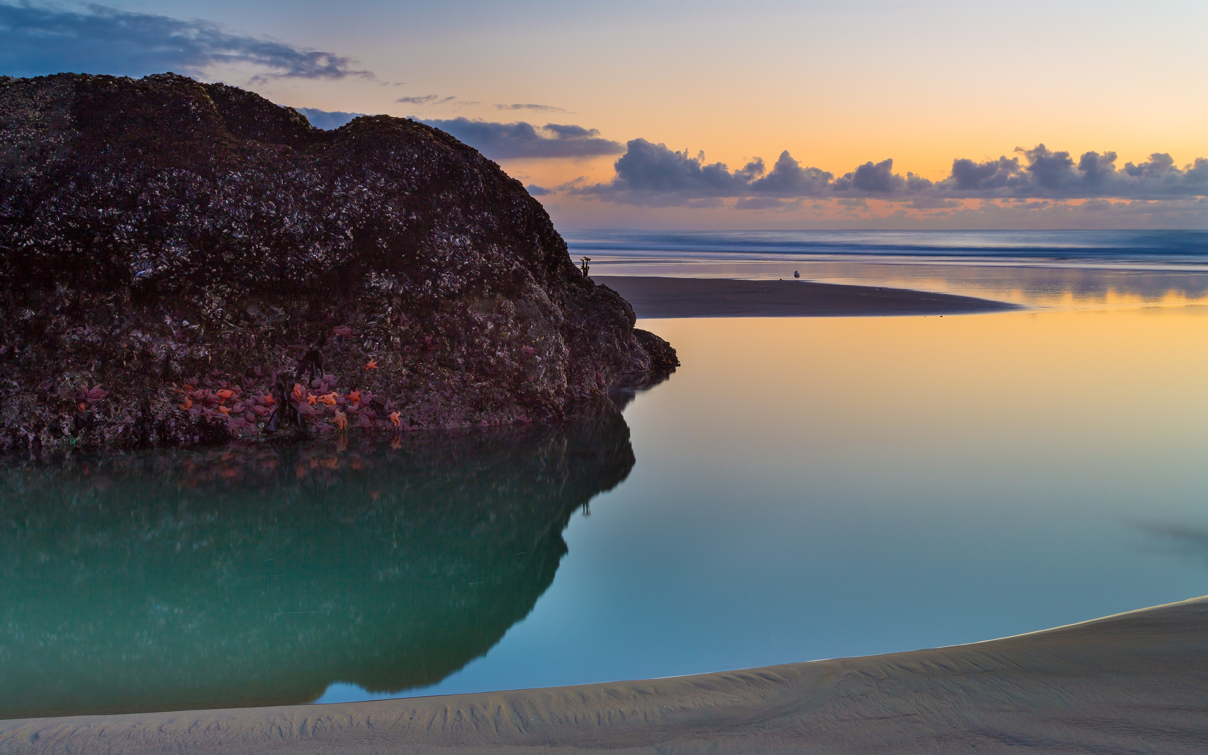 Rock formation in calm water at sunset with reflections HD Wallpaper