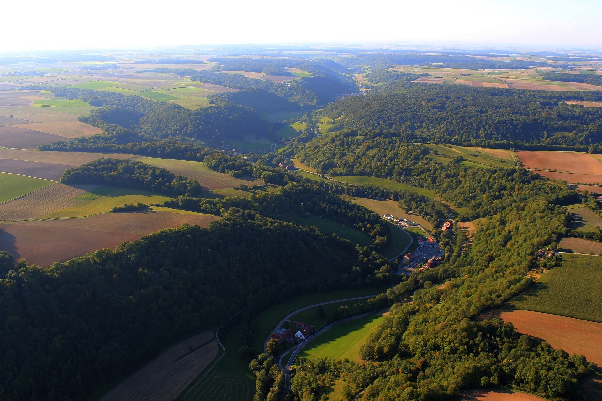 Aerial view of a winding river valley with forests and fields HD Wallpaper