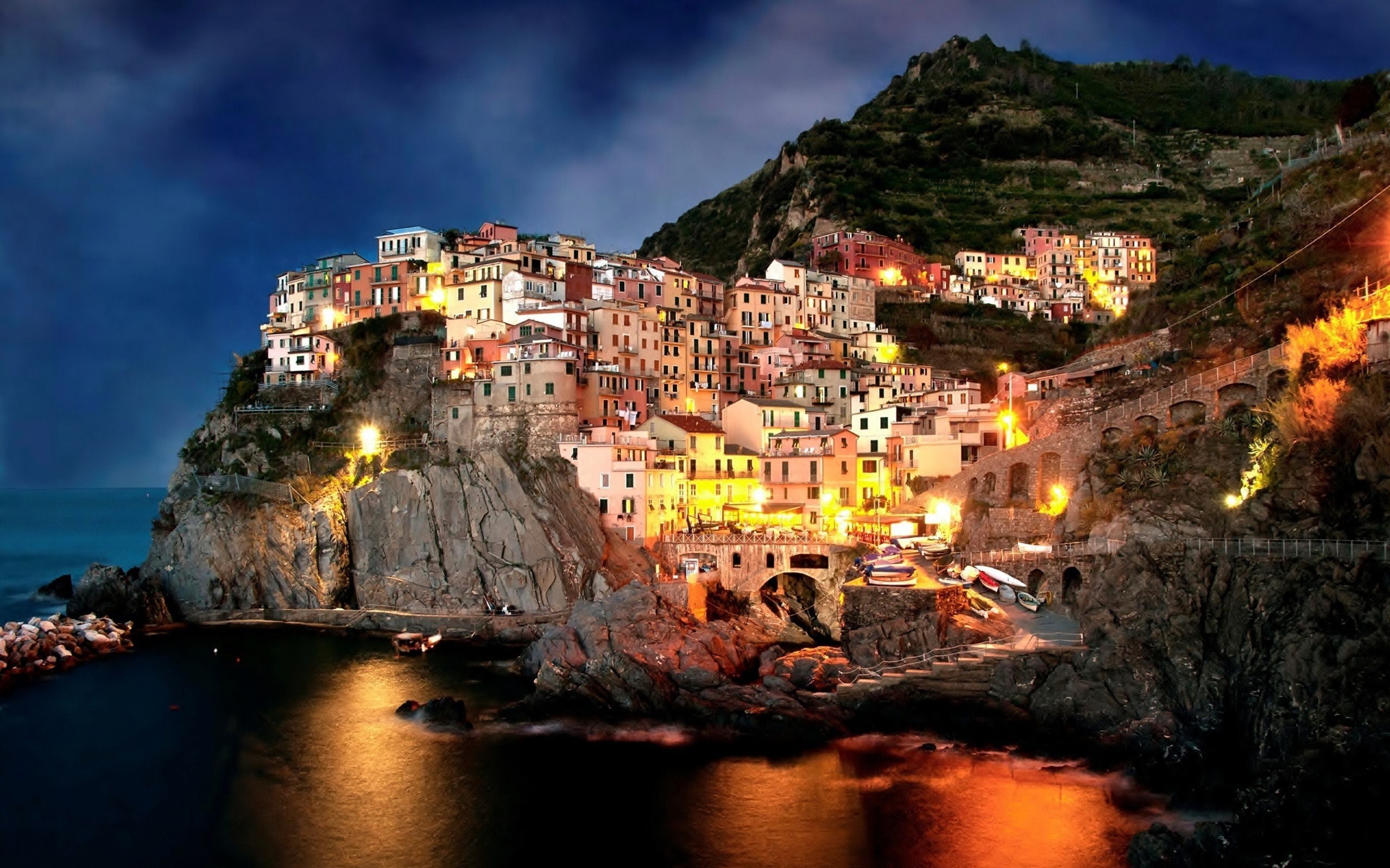Manarola village at night with lights reflecting on the sea HD Wallpaper