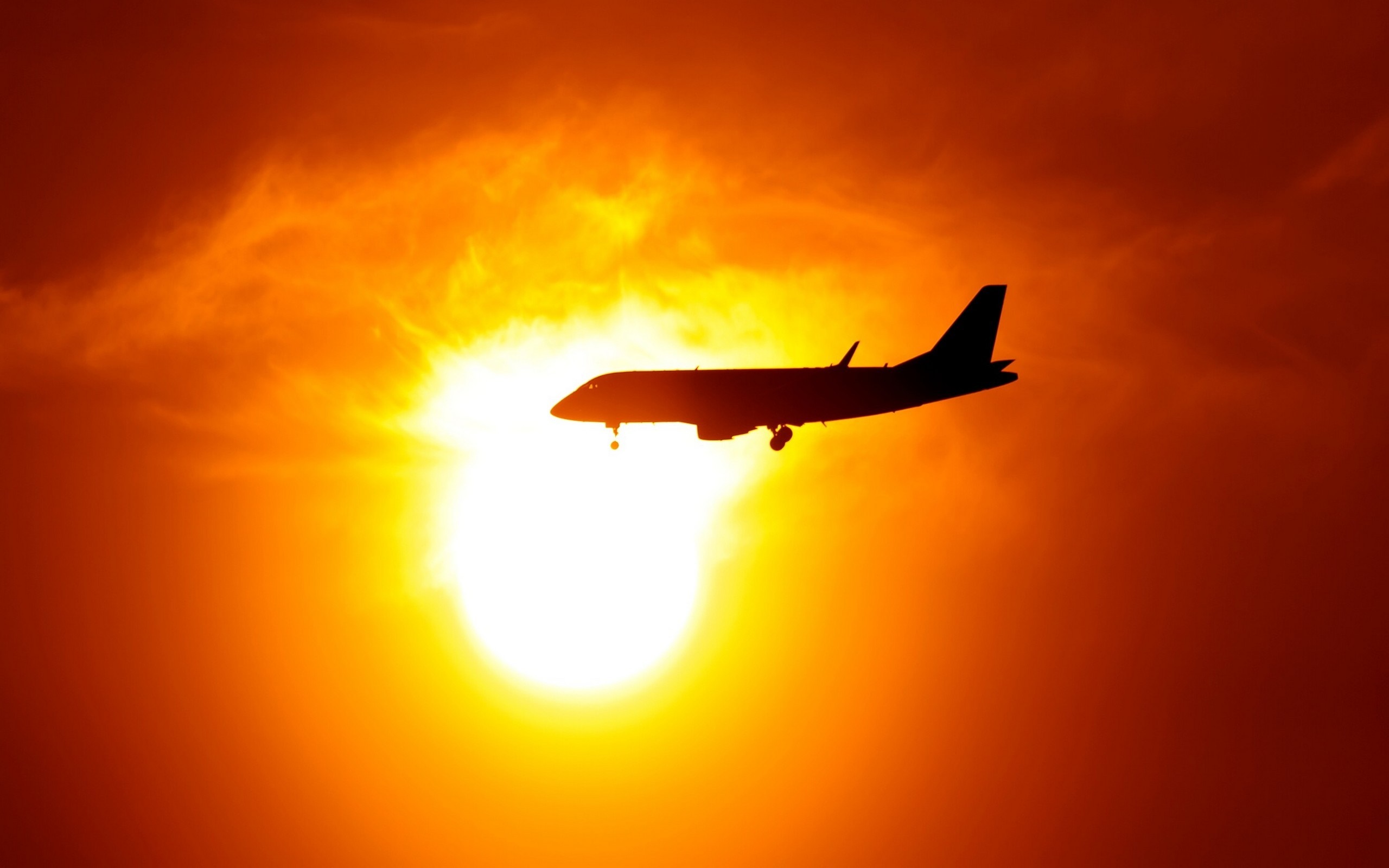 Airplane silhouetted against a bright sunset HD Wallpaper