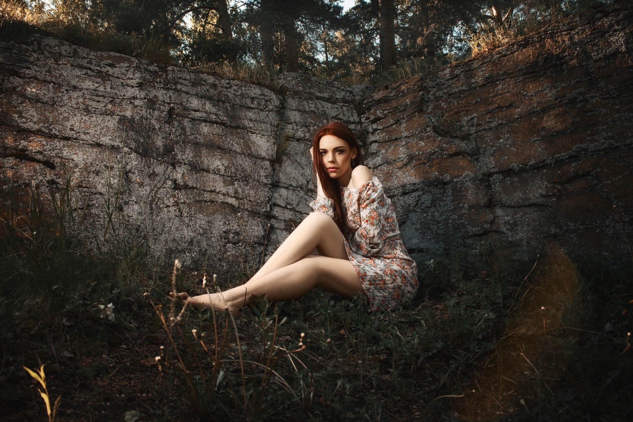 Woman in floral dress sitting by rocks in forest HD Wallpaper