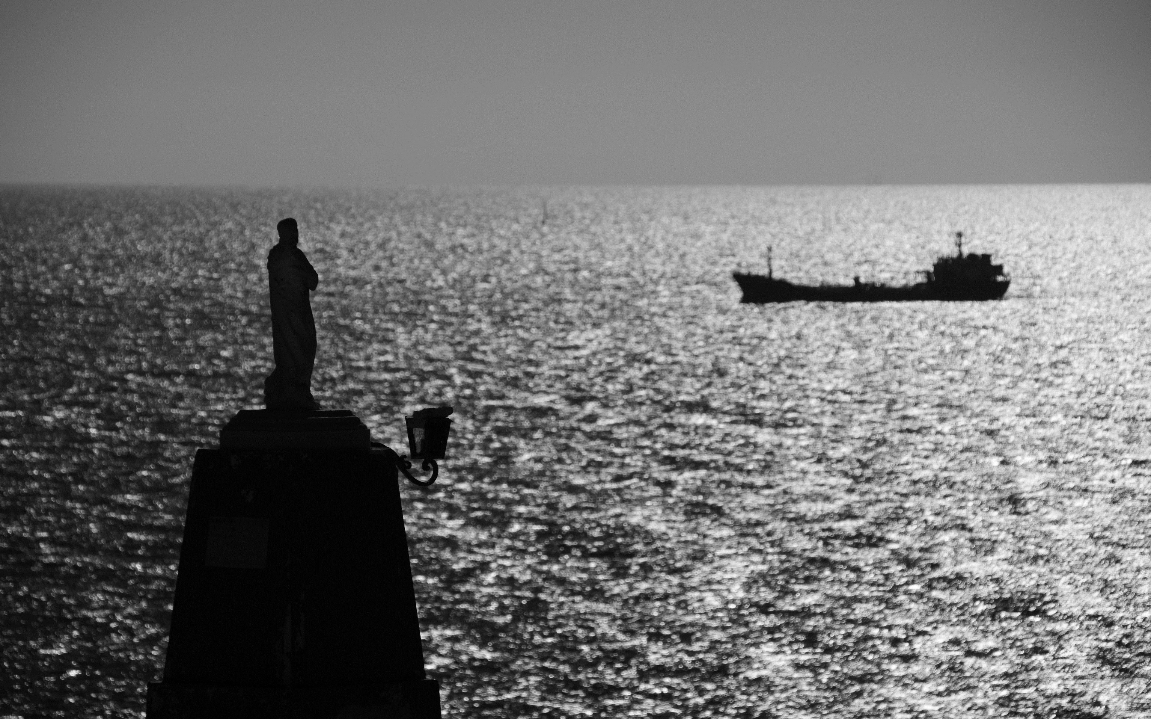 Silhouette of a statue and a ship on the sea HD Wallpaper