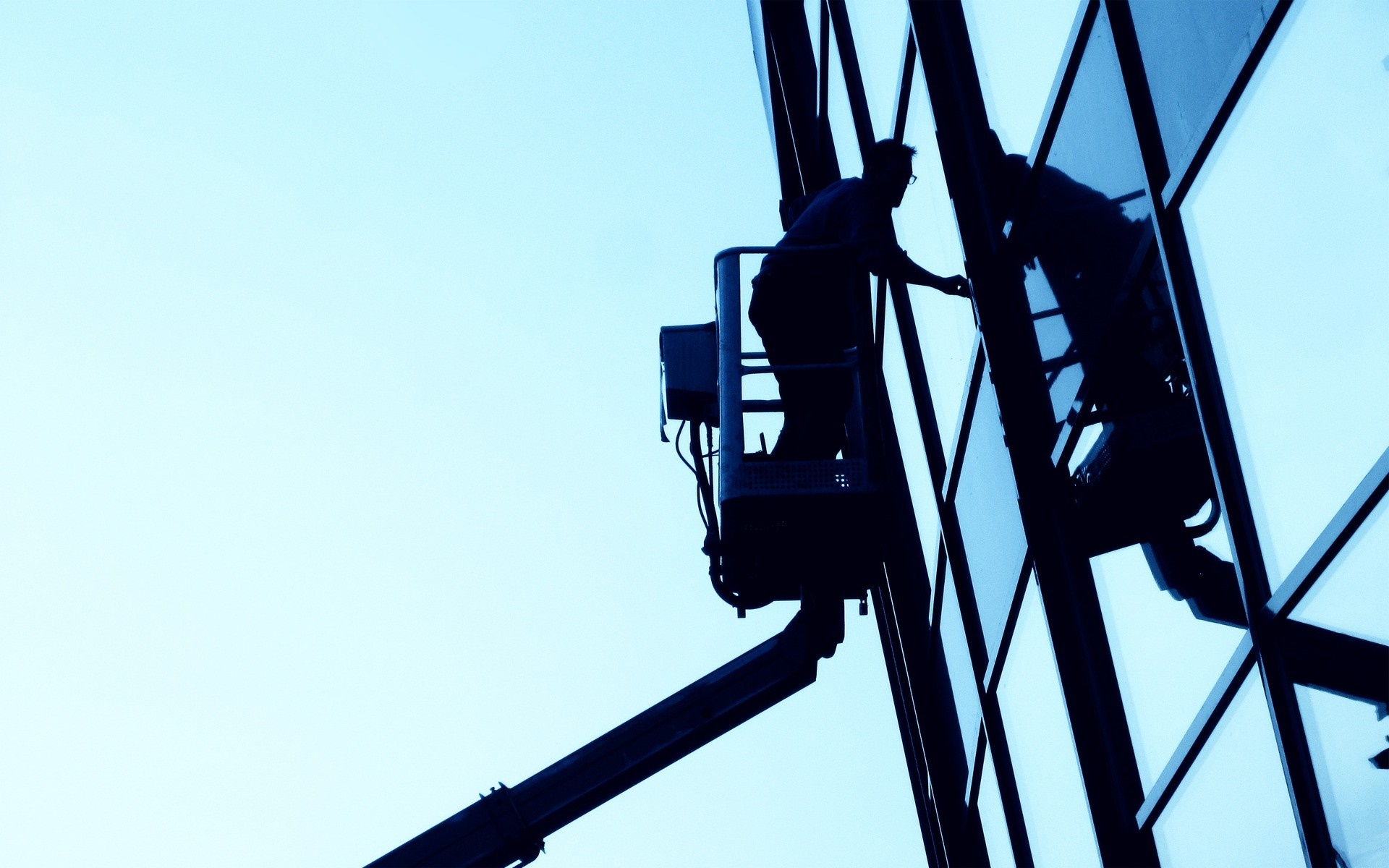 Silhouette of a window cleaner in a cherry picker HD Wallpaper