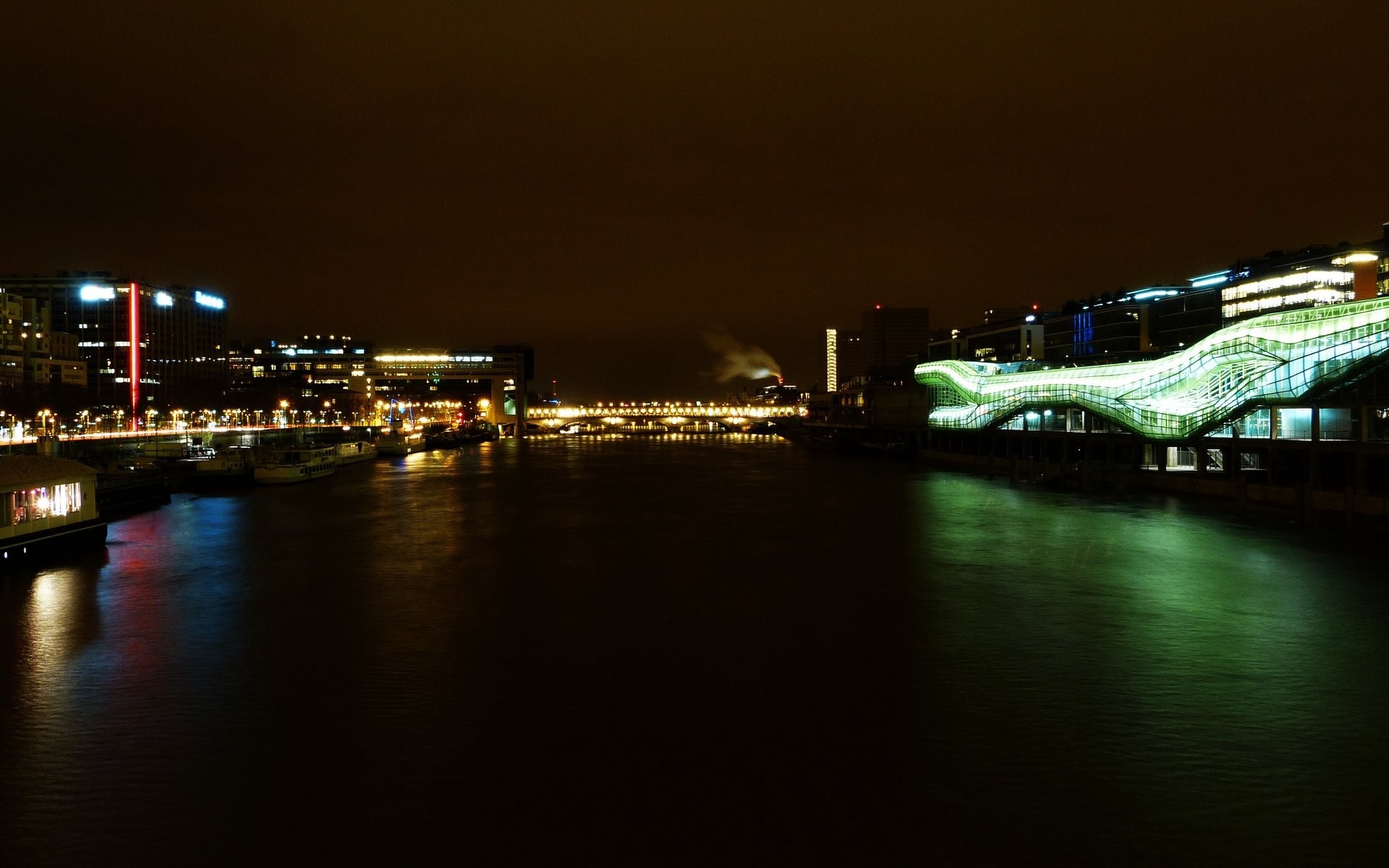 Cityscape at night with river and illuminated buildings HD Wallpaper