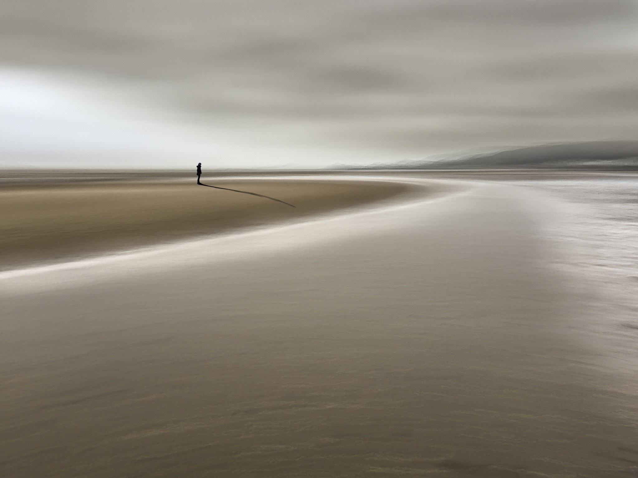 Lone figure on a sandy beach with ocean waves HD Wallpaper