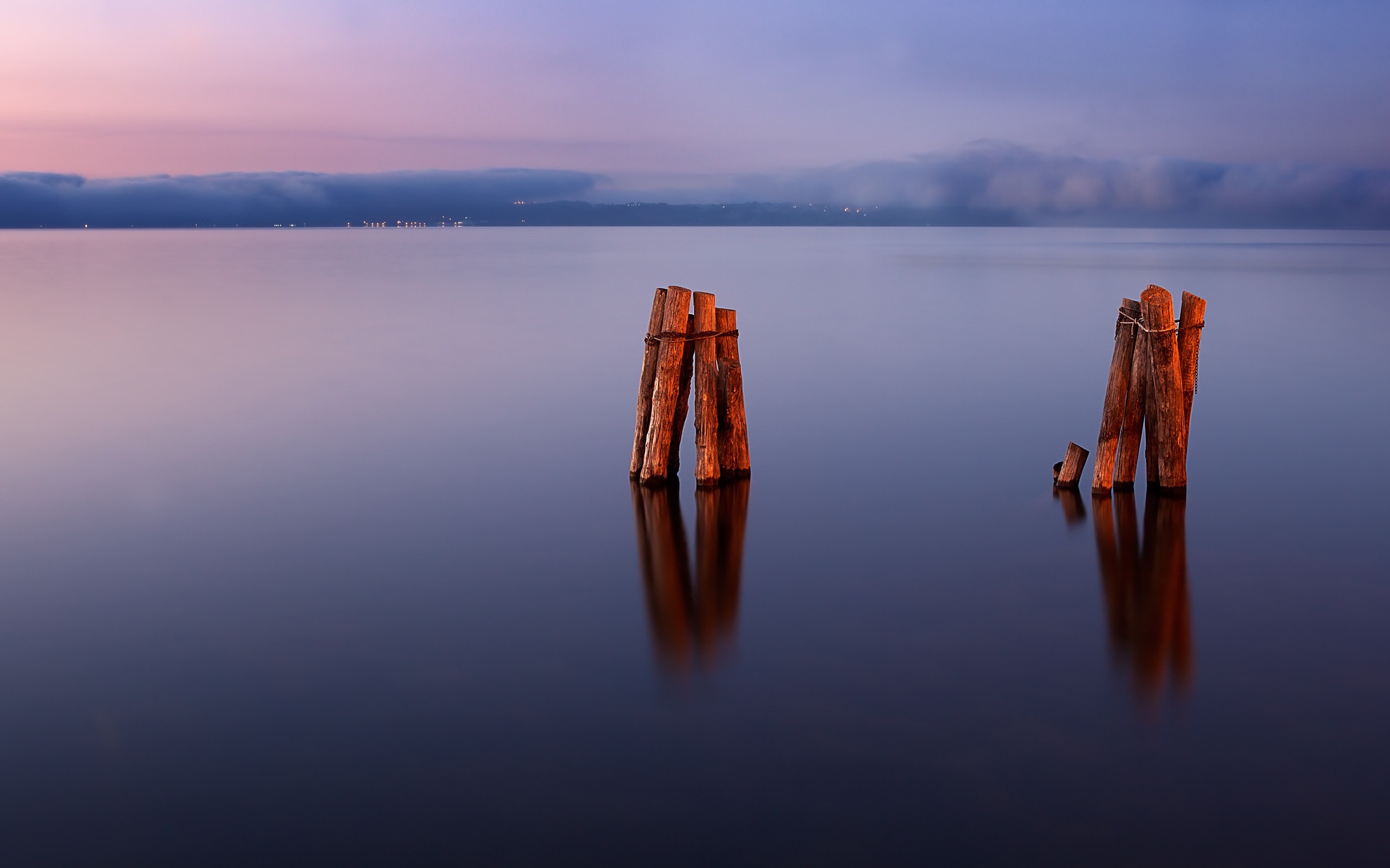 Wooden posts in calm water at sunset HD Wallpaper