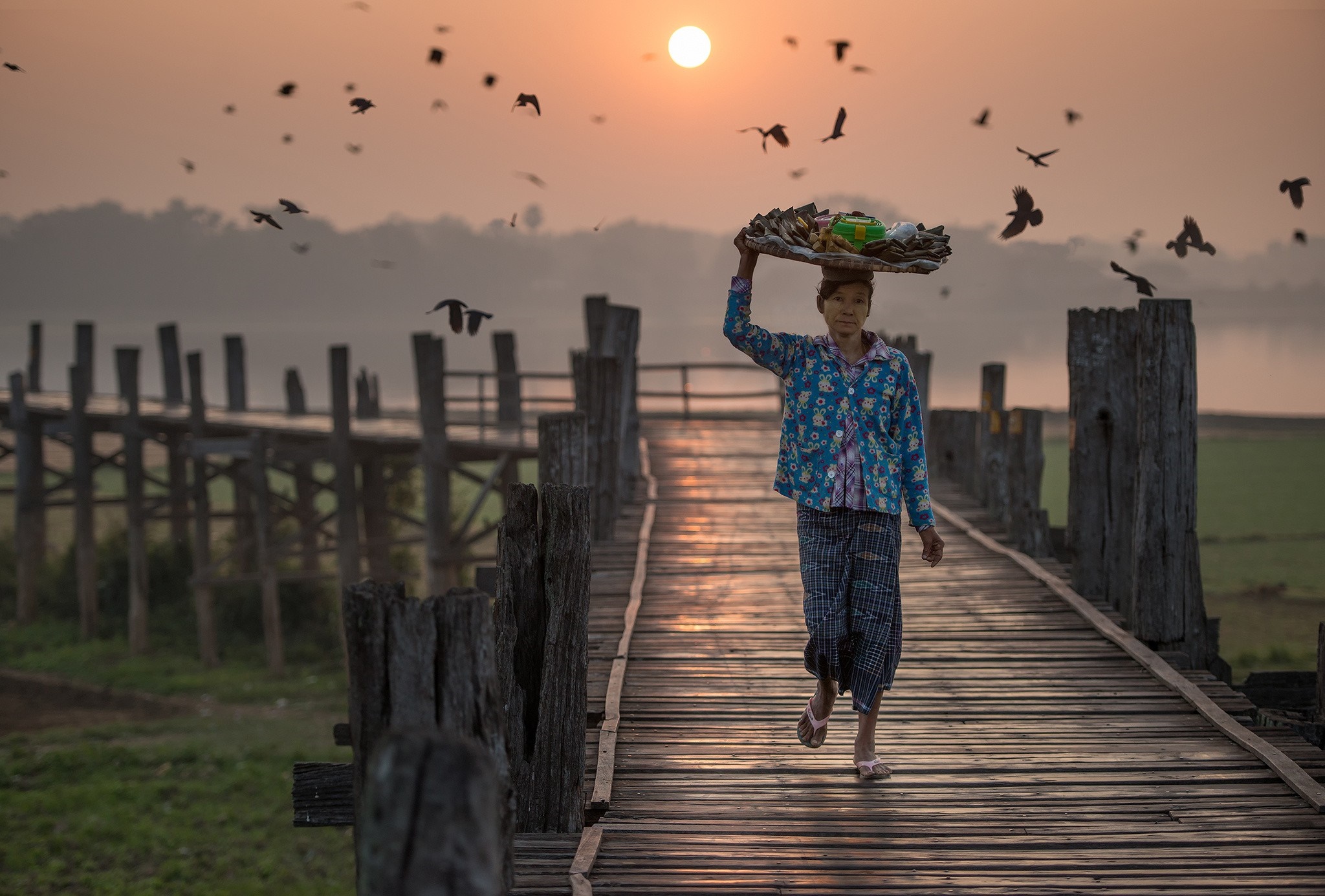 Woman carrying basket on U Bein Bridge at sunset HD Wallpaper