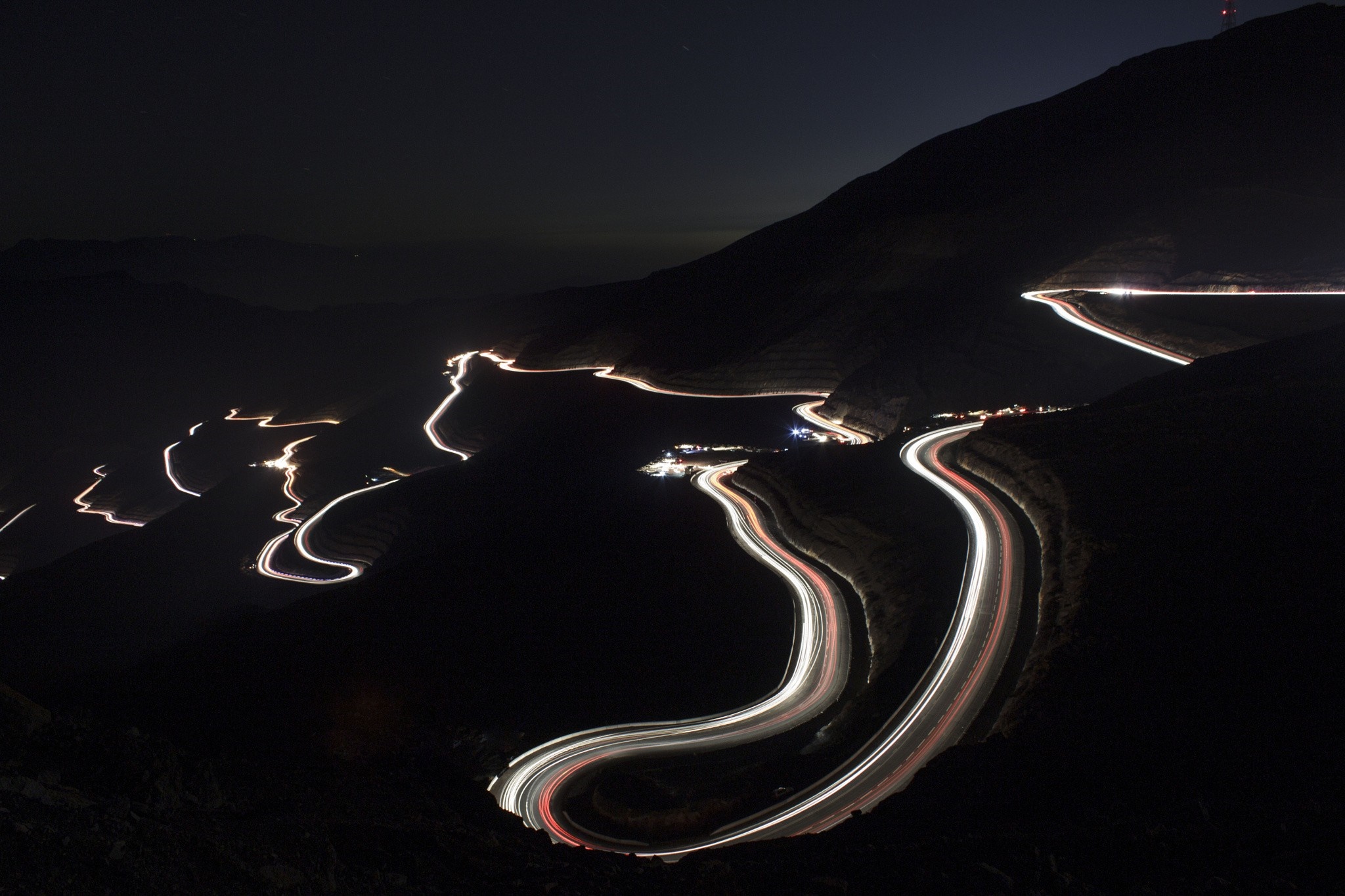 Nighttime mountain road with light trails HD Wallpaper