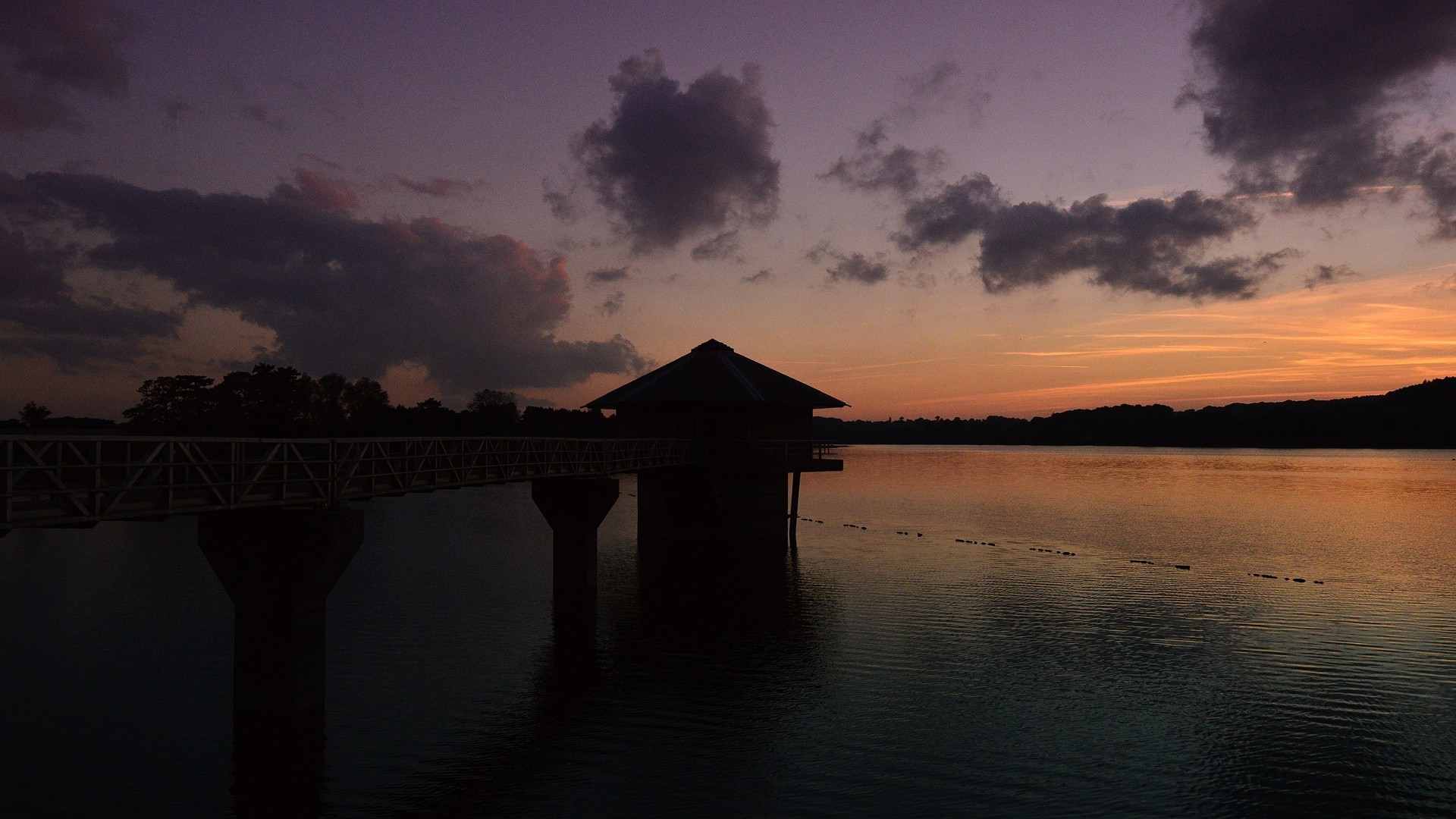 Sunset over a lake with a water tower and bridge HD Wallpaper
