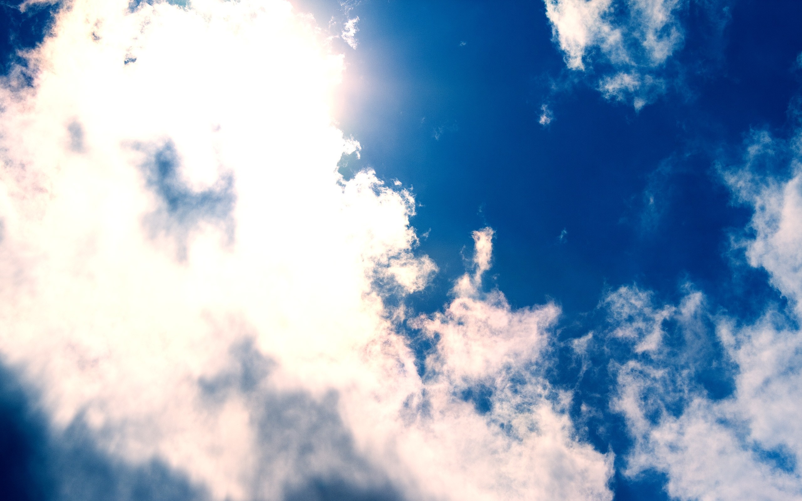 Sunlight shining through clouds in a blue sky HD Wallpaper