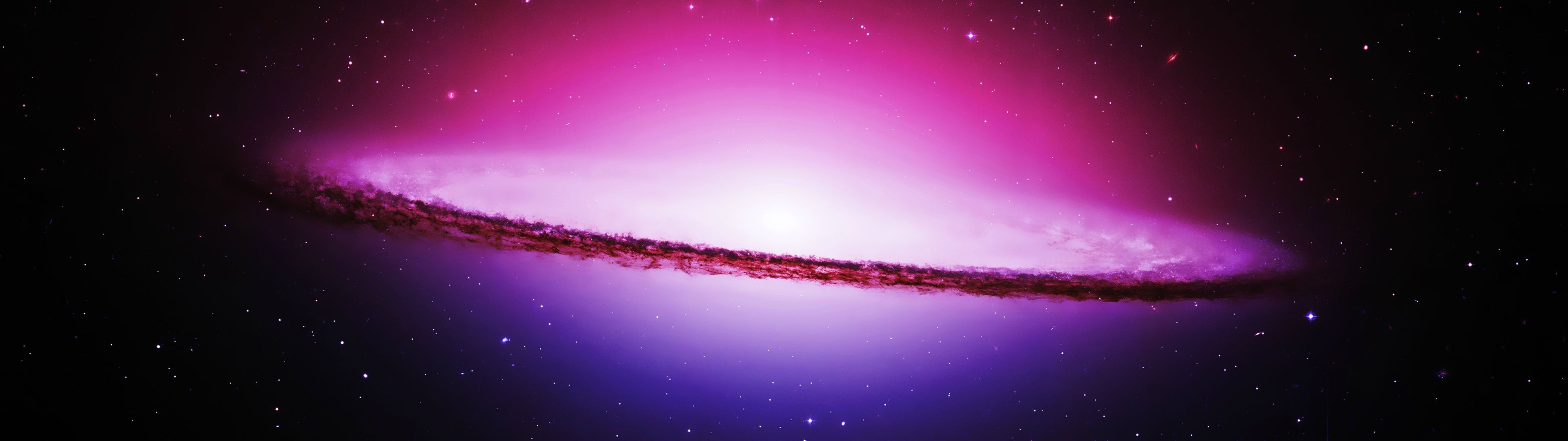 A spiral galaxy with a bright core and dark dust lane HD Wallpaper