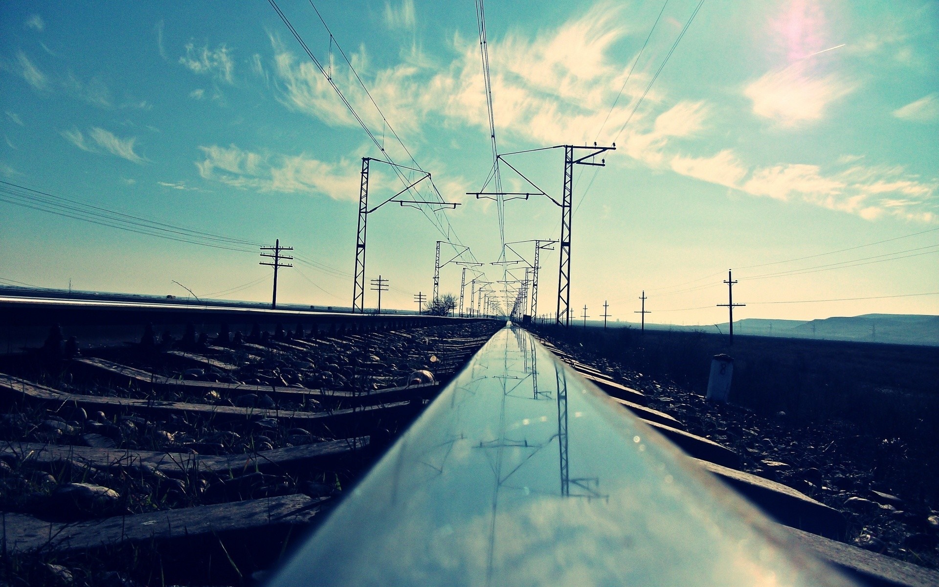 Railway tracks with overhead power lines under a cloudy sky HD Wallpaper
