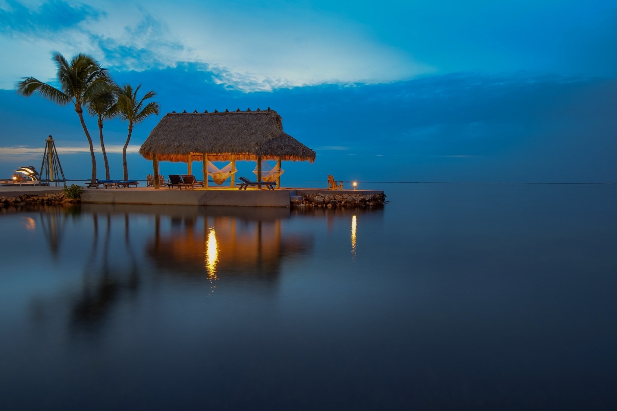 Tropical hut with hammocks over the water at dusk HD Wallpaper